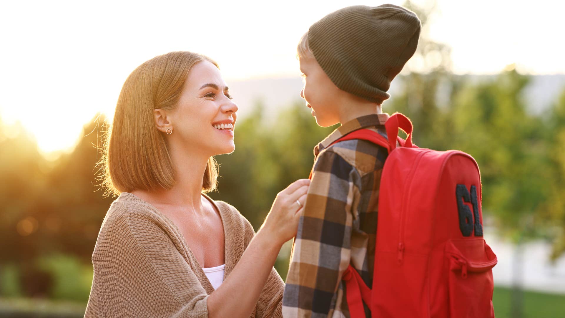 Mom smiling and fixing her son's jacket before school.