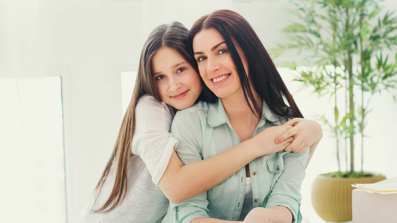 preteen daughter hugging mom smiling