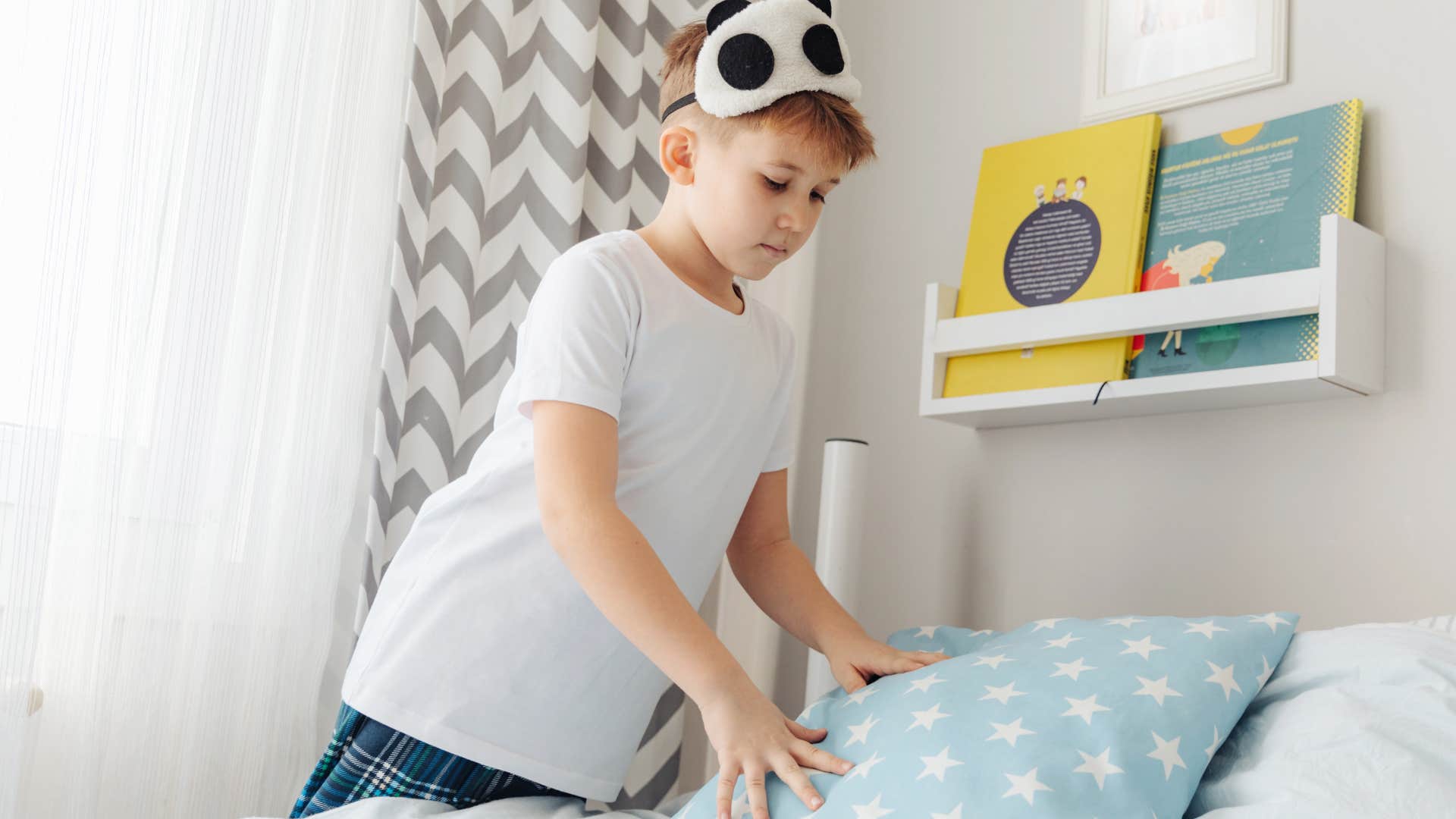 Young boy making his bed in the morning.