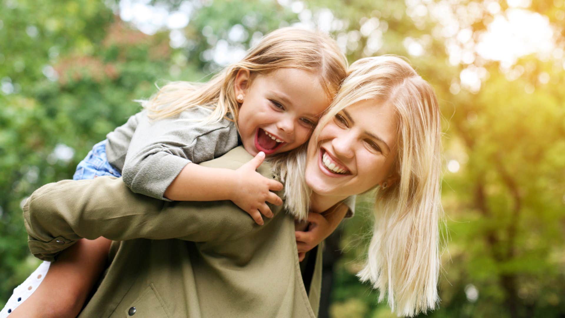 Young mom smiling and holding her daughter.