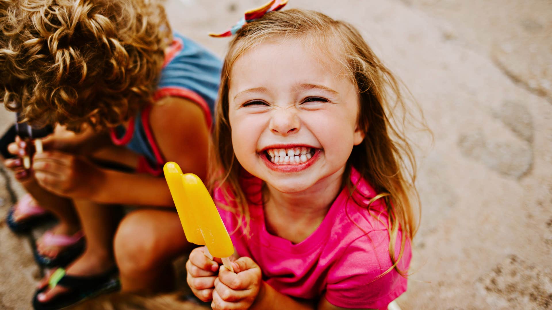 Young girl smiling and holding a popsicle. 