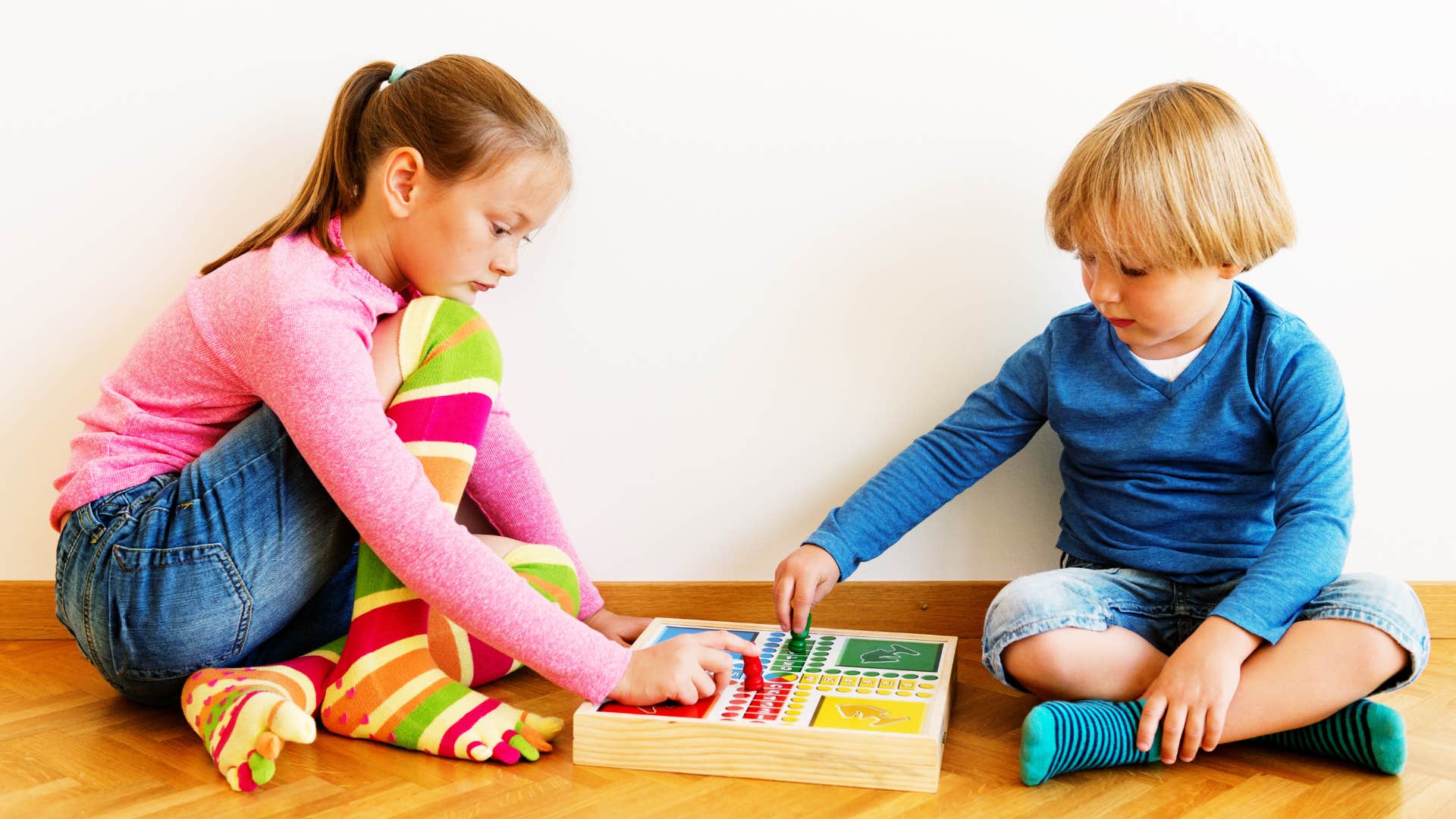 Two young siblings playing a game and wearing socks.