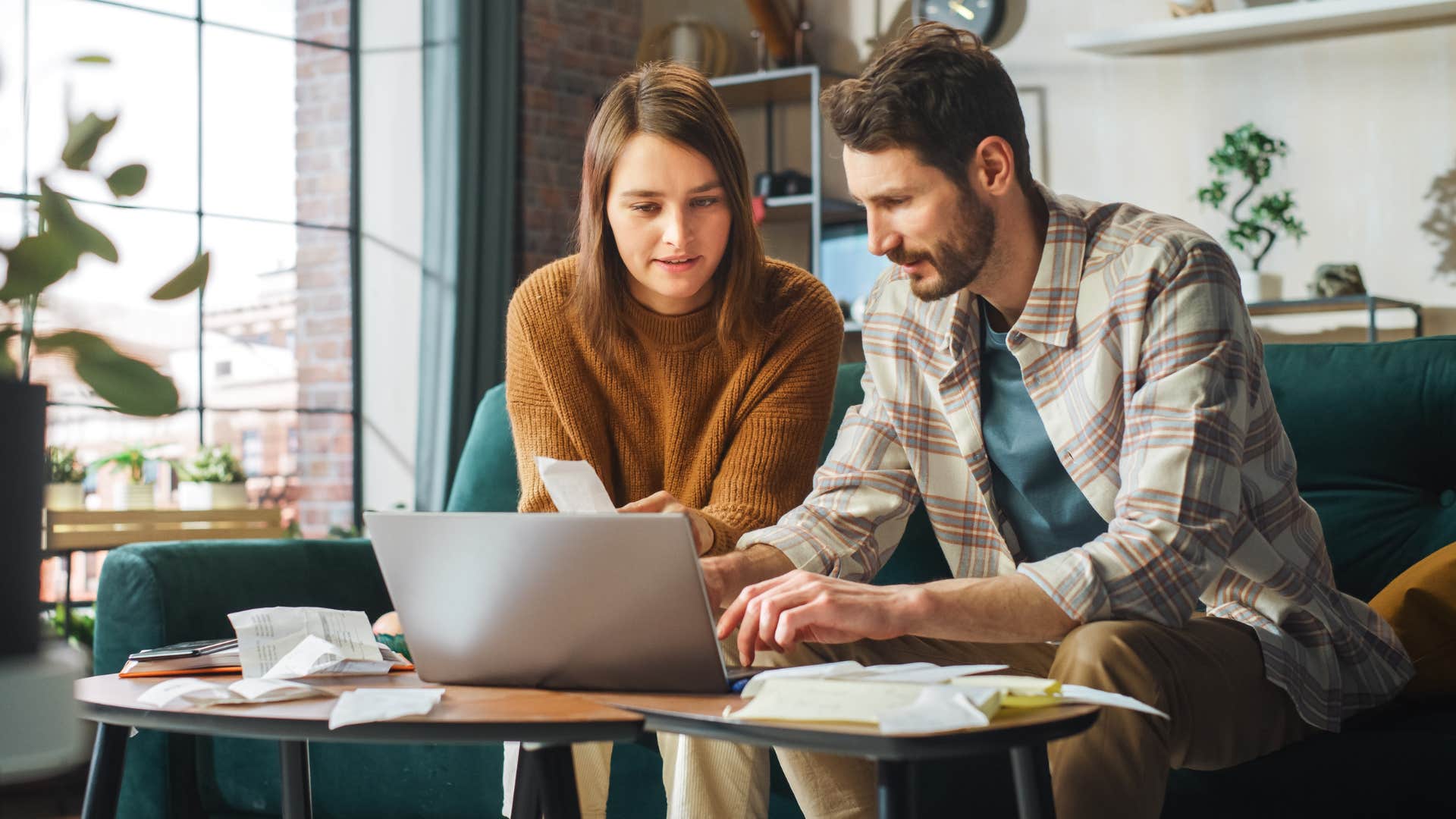 Couple sitting on the couch doing bills.