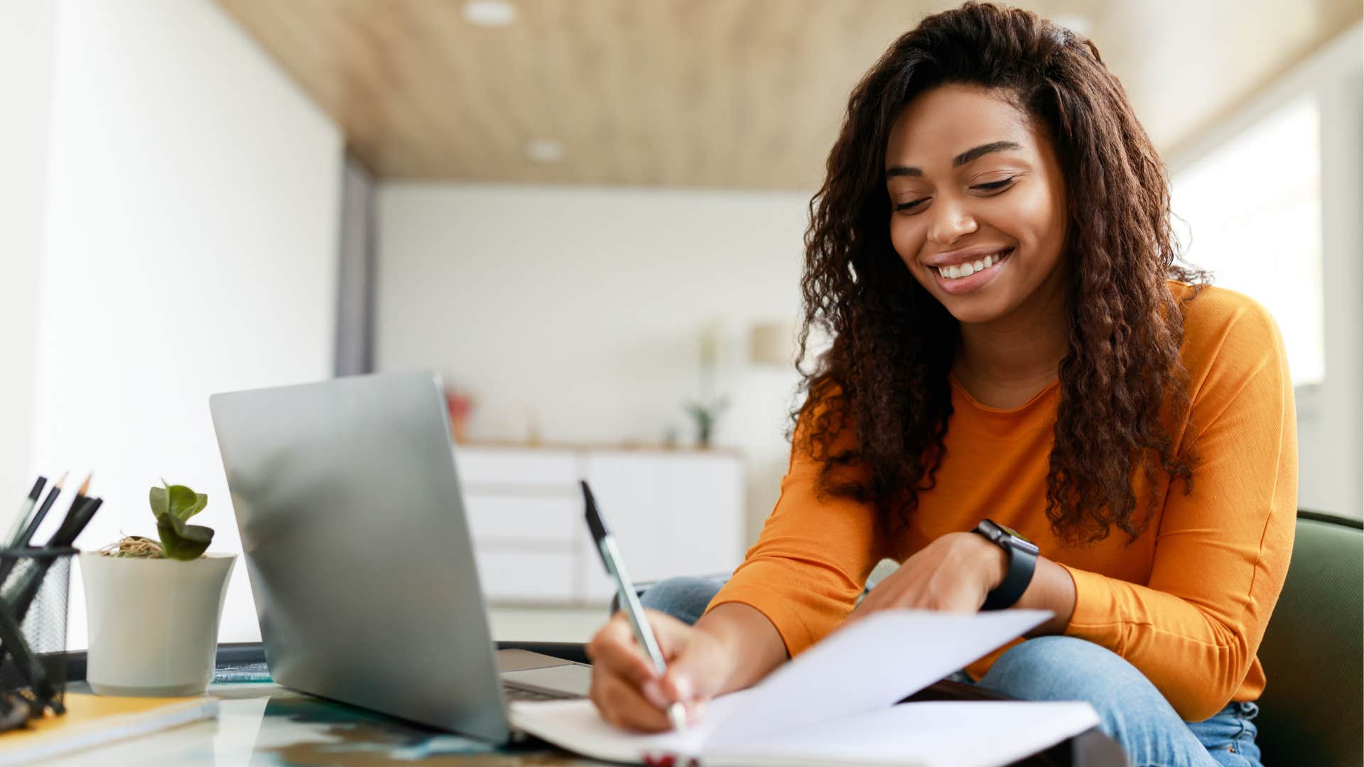 Woman smiling while writing in a notebook.