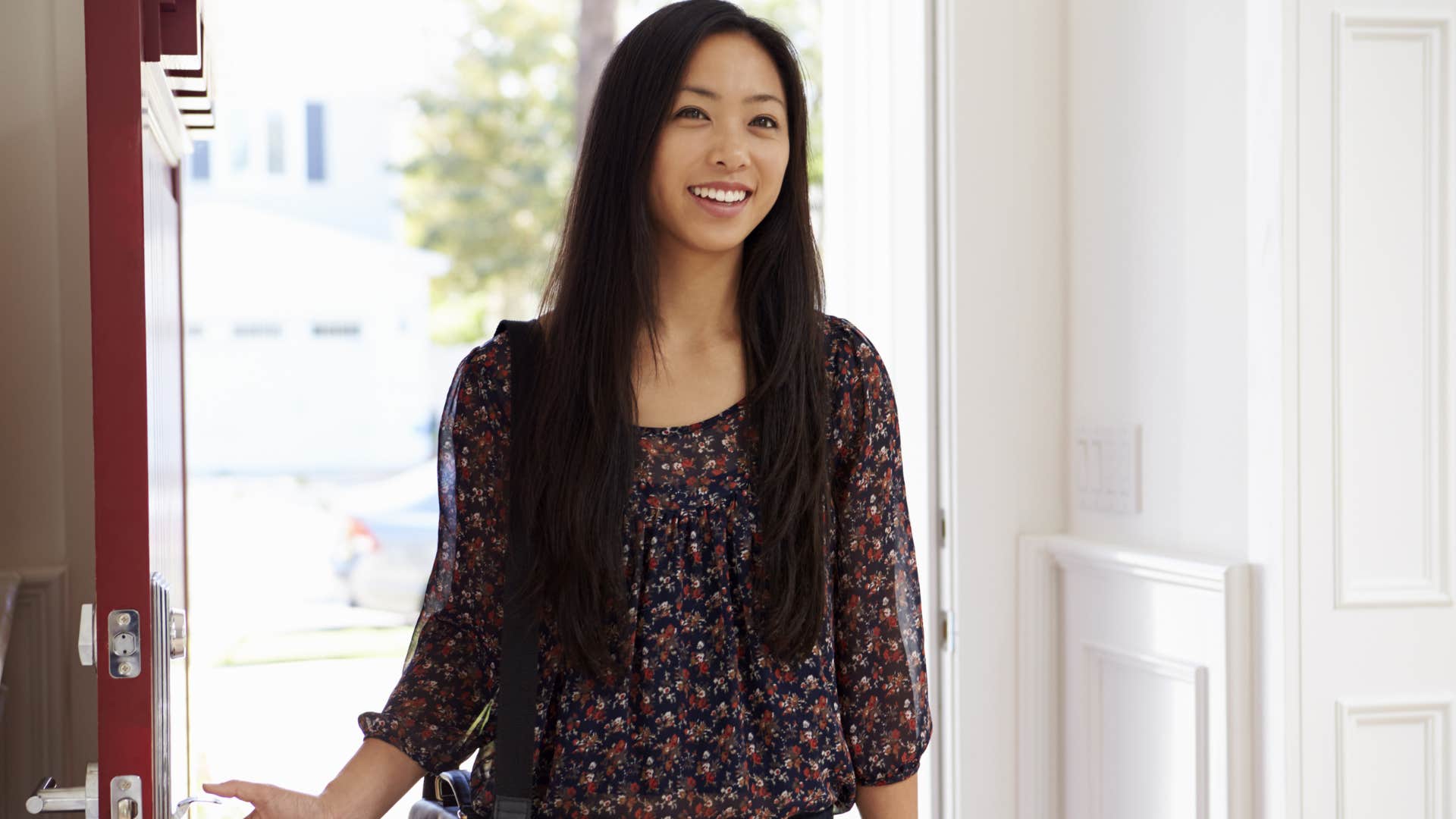 Woman walking in the front door smiling.