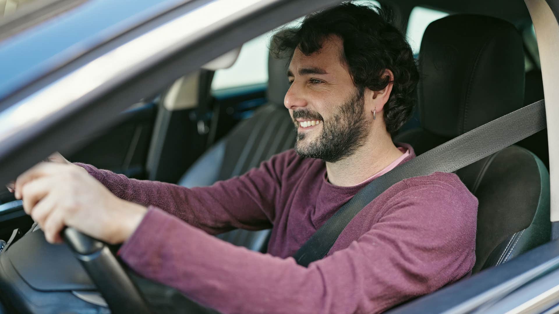 Young man smiling while driving a car.