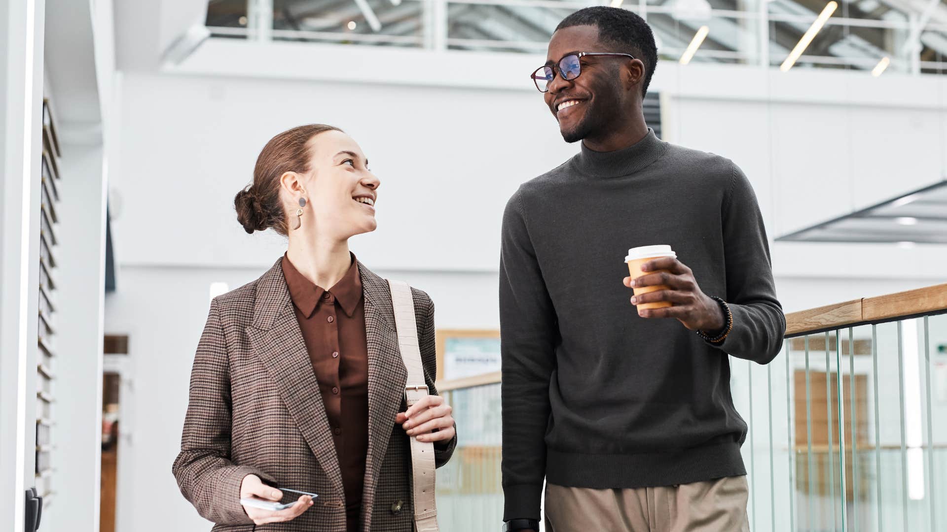 Two Gen Z co-workers walking and talking together.