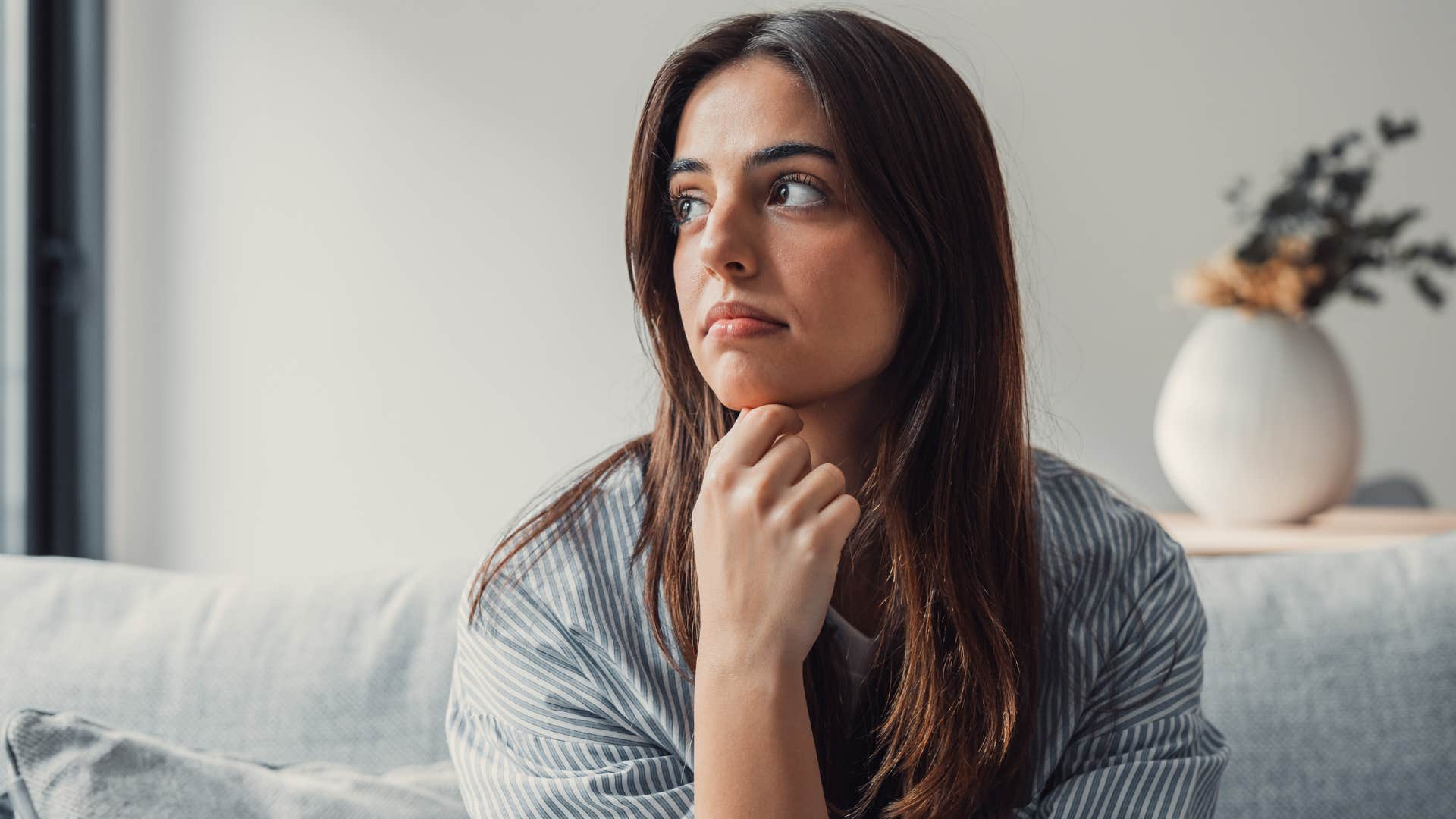 Young woman looking sad on her couch.