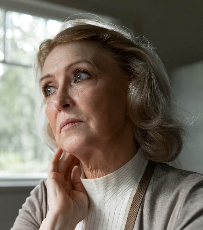 Concerned woman looks out window