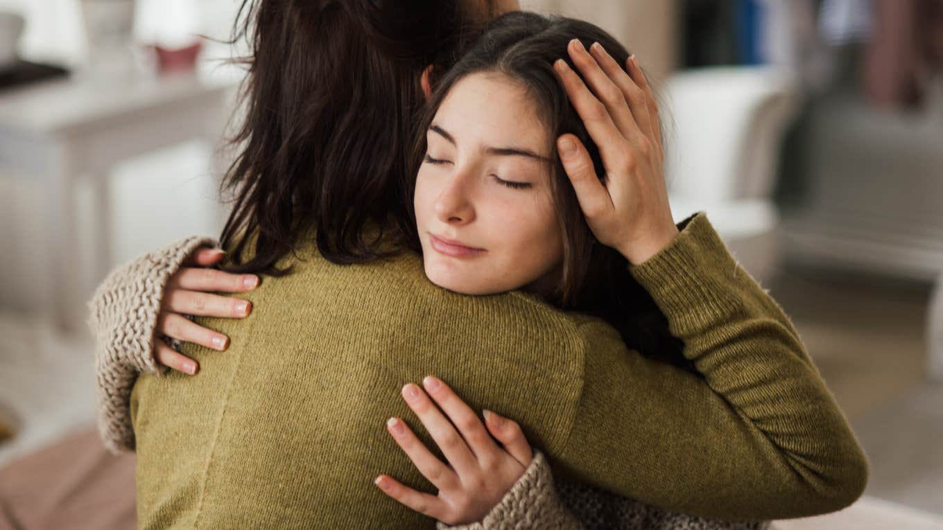 Teenage girl hugging her mother at home.