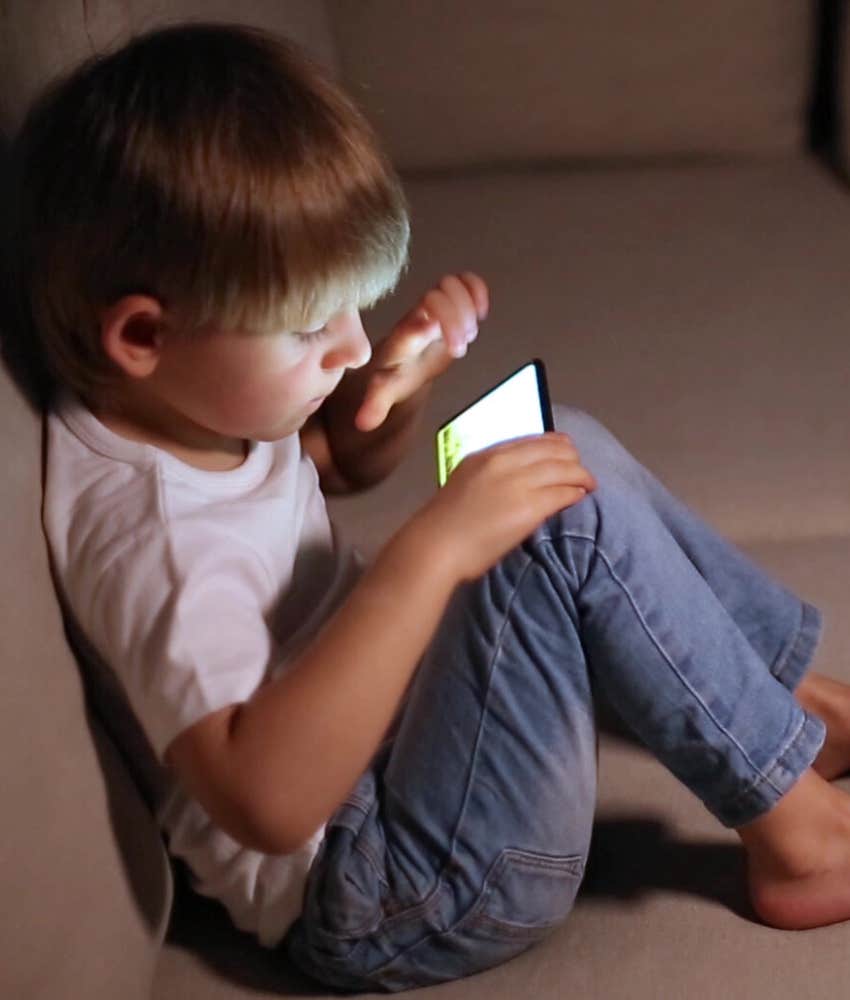 toddler sitting on couch with phone