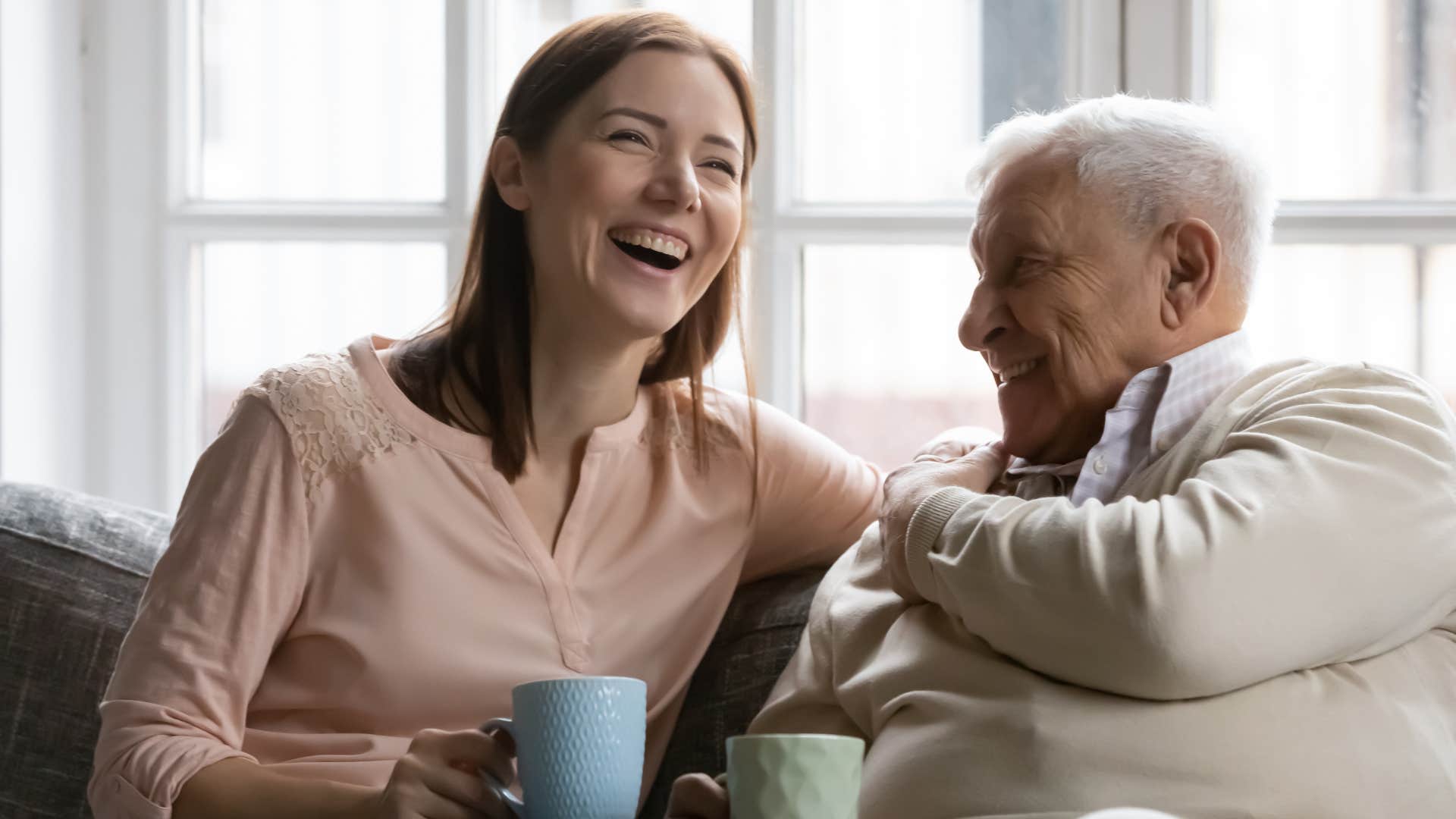 Older man smiling and laughing with his adult daughter.