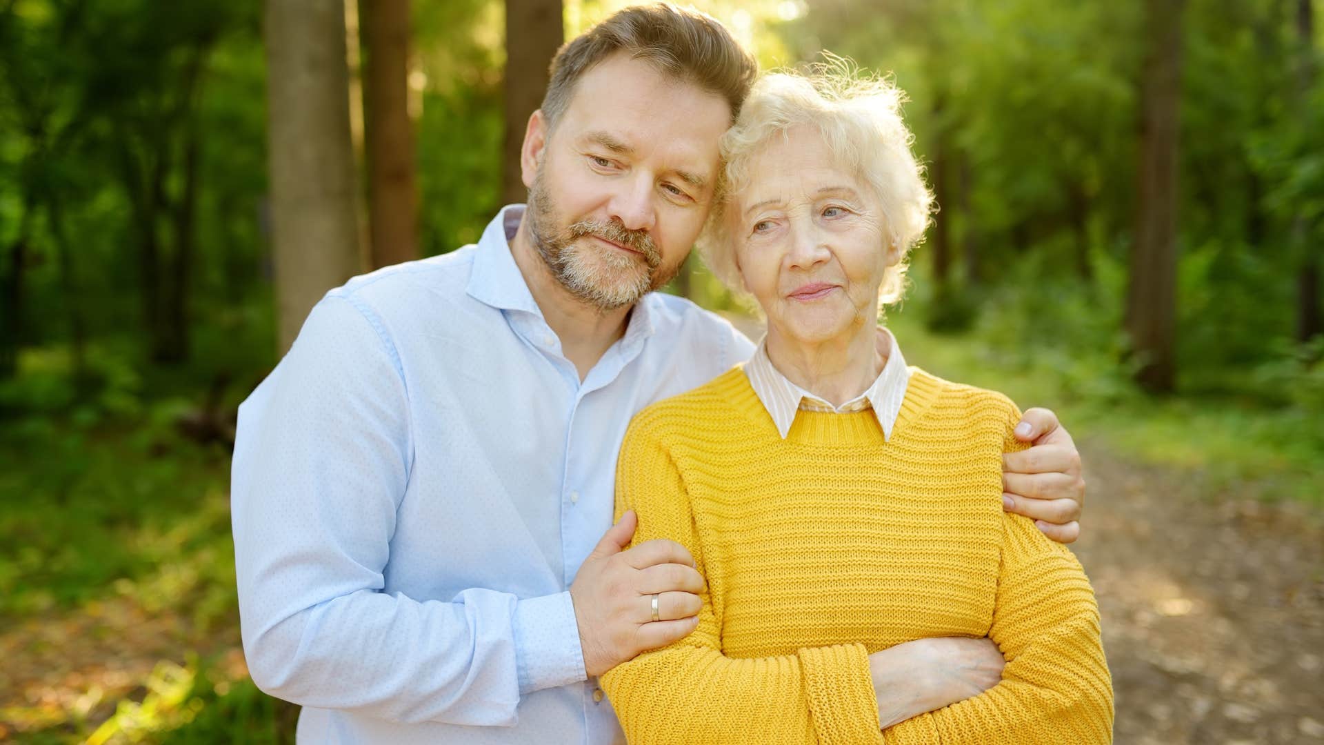 Older man hugging his mom outside.