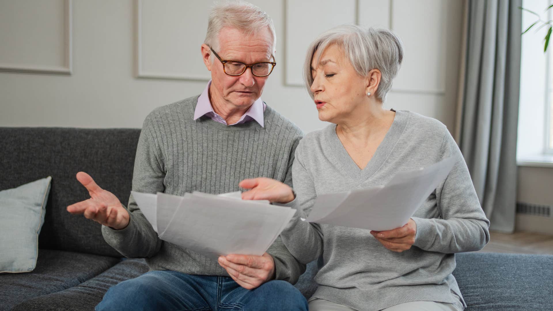 Older couple looking upset staring at papers.