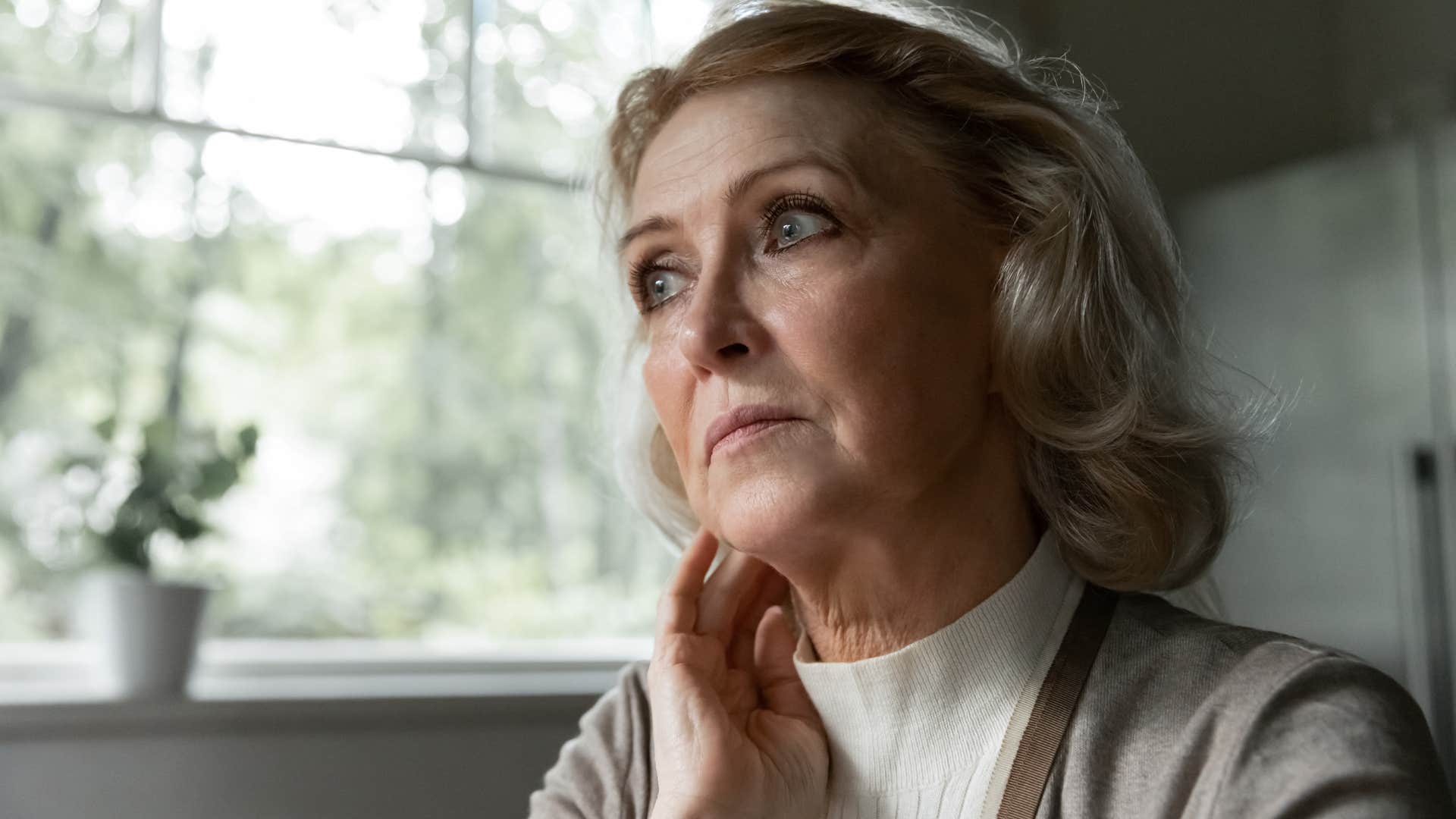 Older woman looking upset sitting at home.