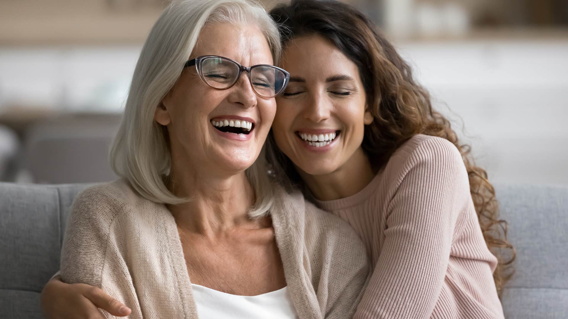 Adult daughter smiling and hugging her mother.