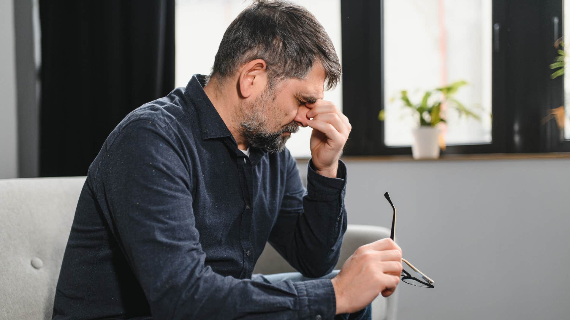 Adult man looking annoyed and upset on the couch.