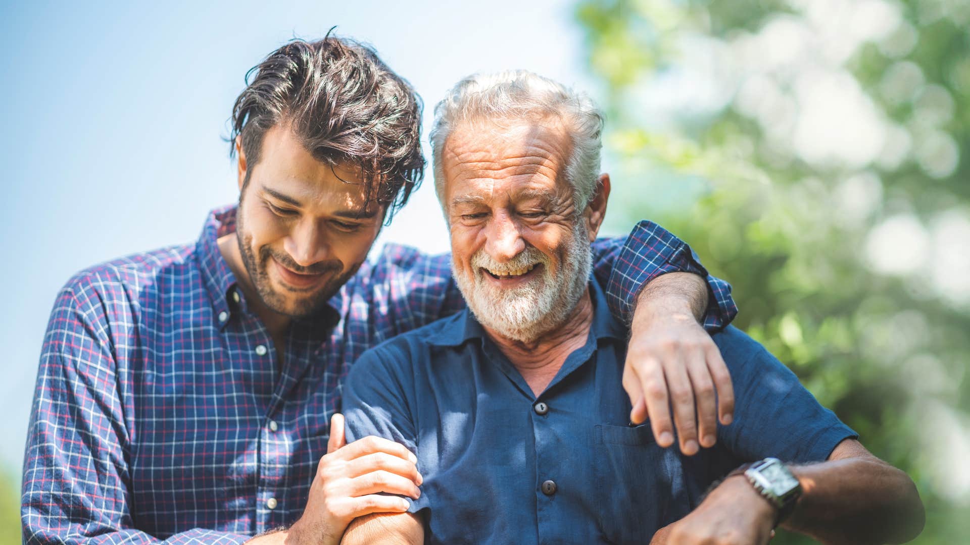 Adult son hugging his older dad outside.