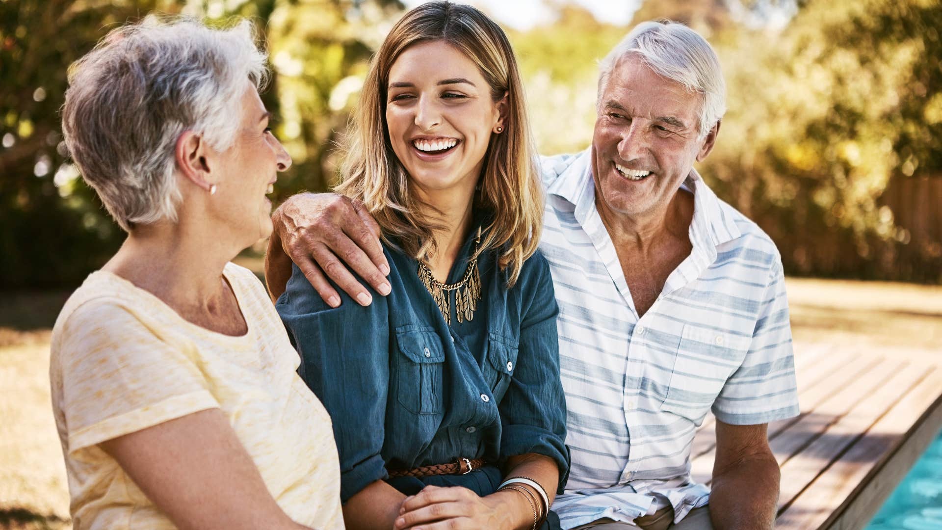 Adult daughter smiling in between her two parents.