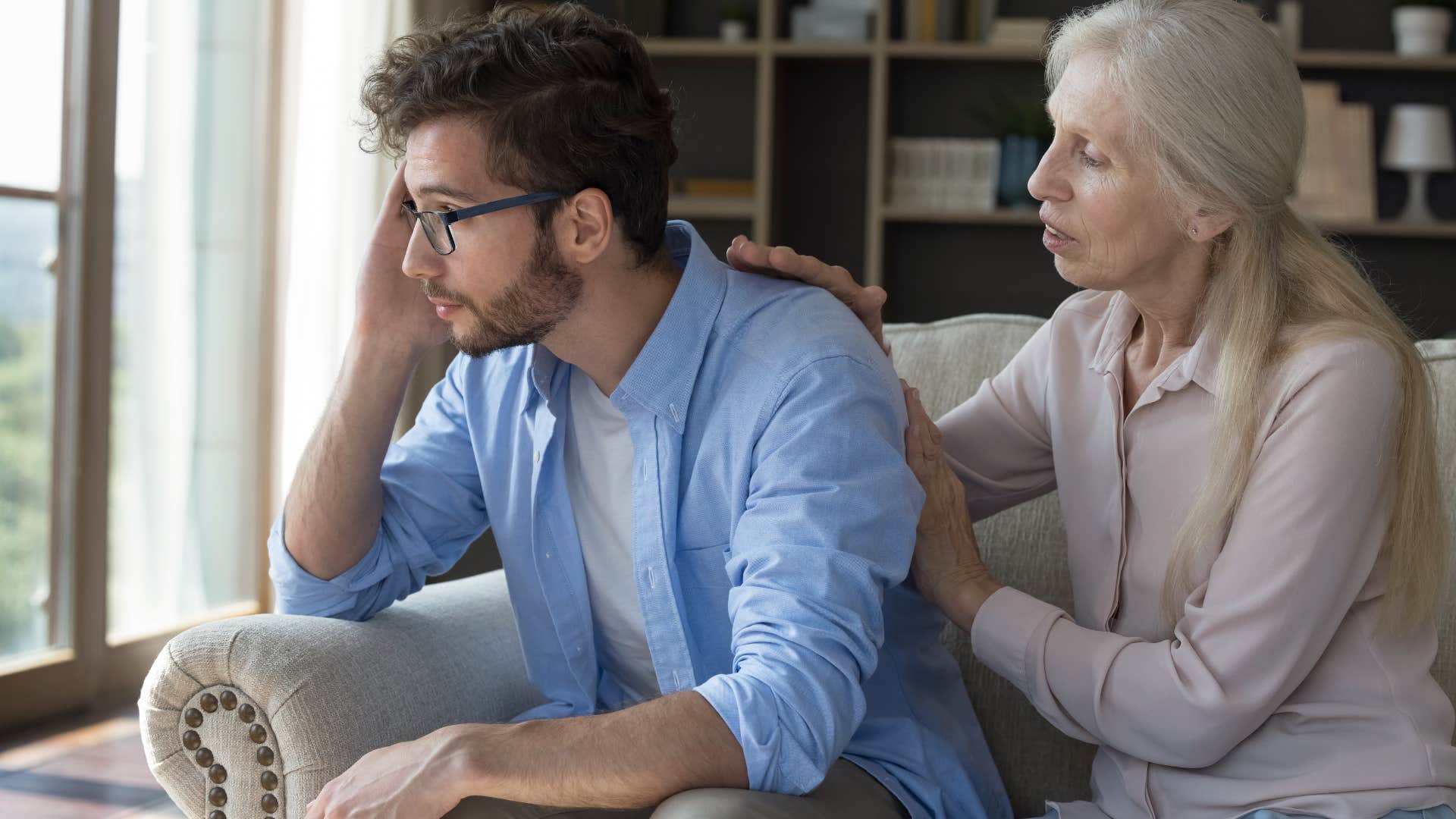 Older woman comforting her sad adult son.