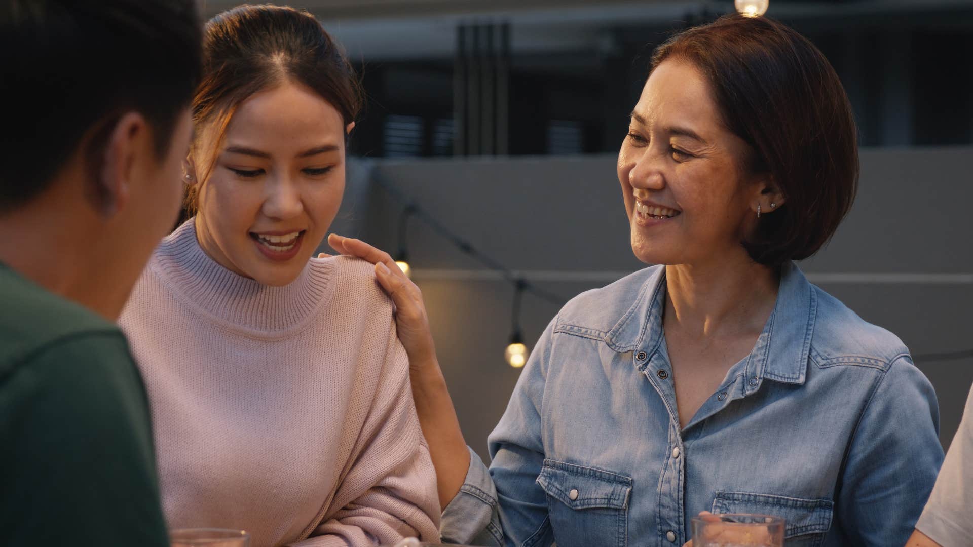 Woman smiling next to her adult daughter at dinner.