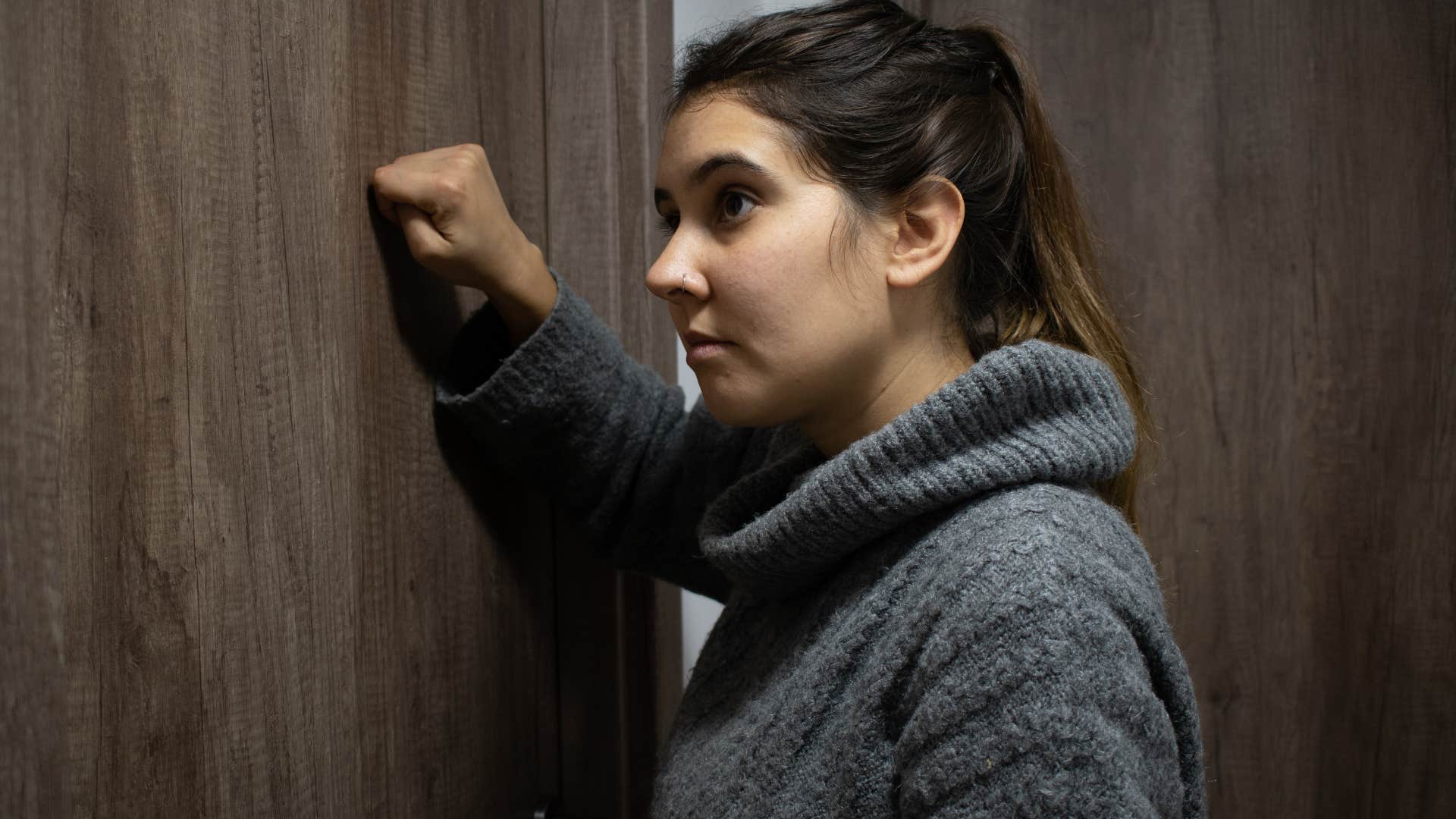 Woman looking sad and knocking on a bedroom door.