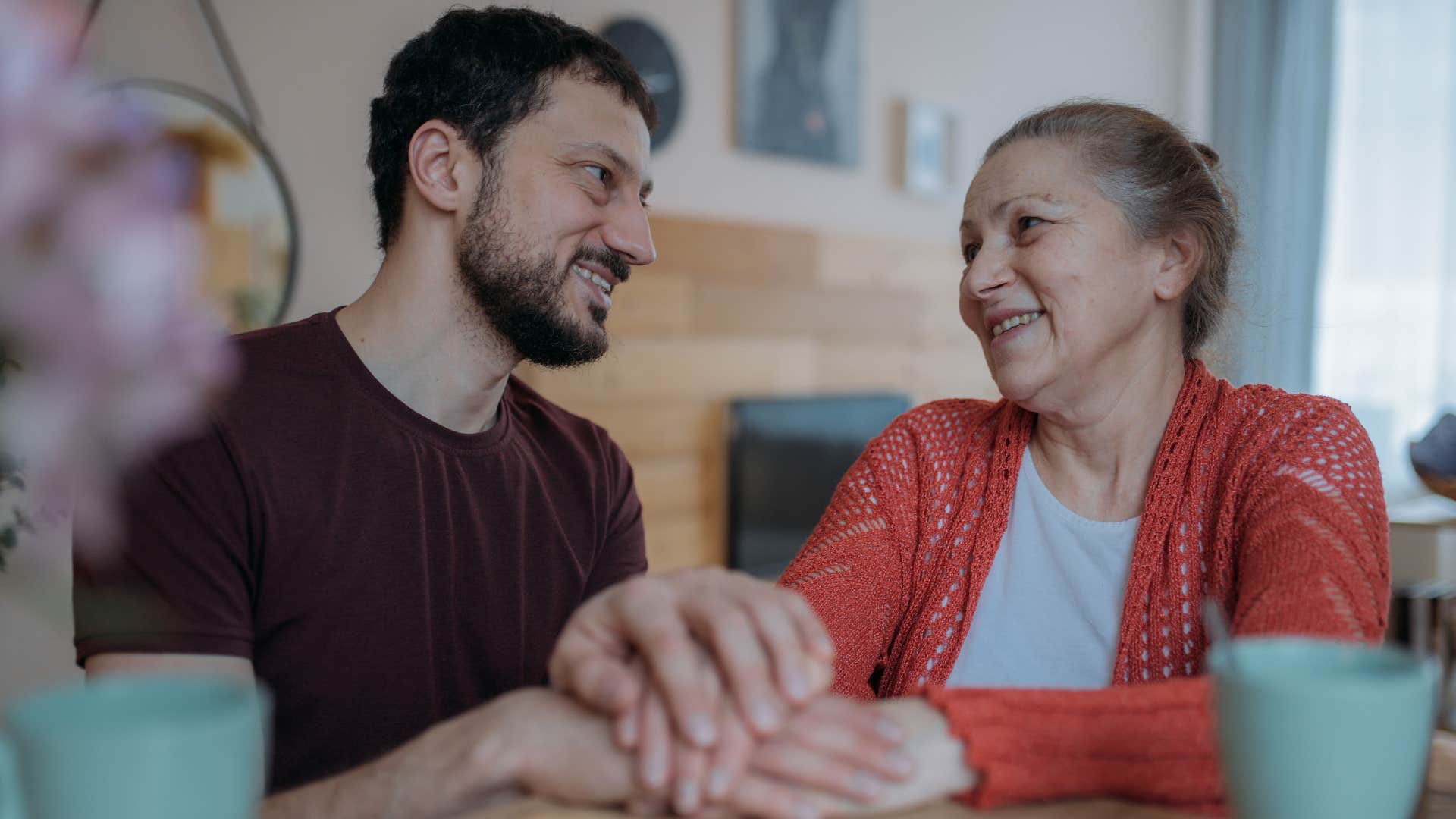 Adult son holding his mother's hand.