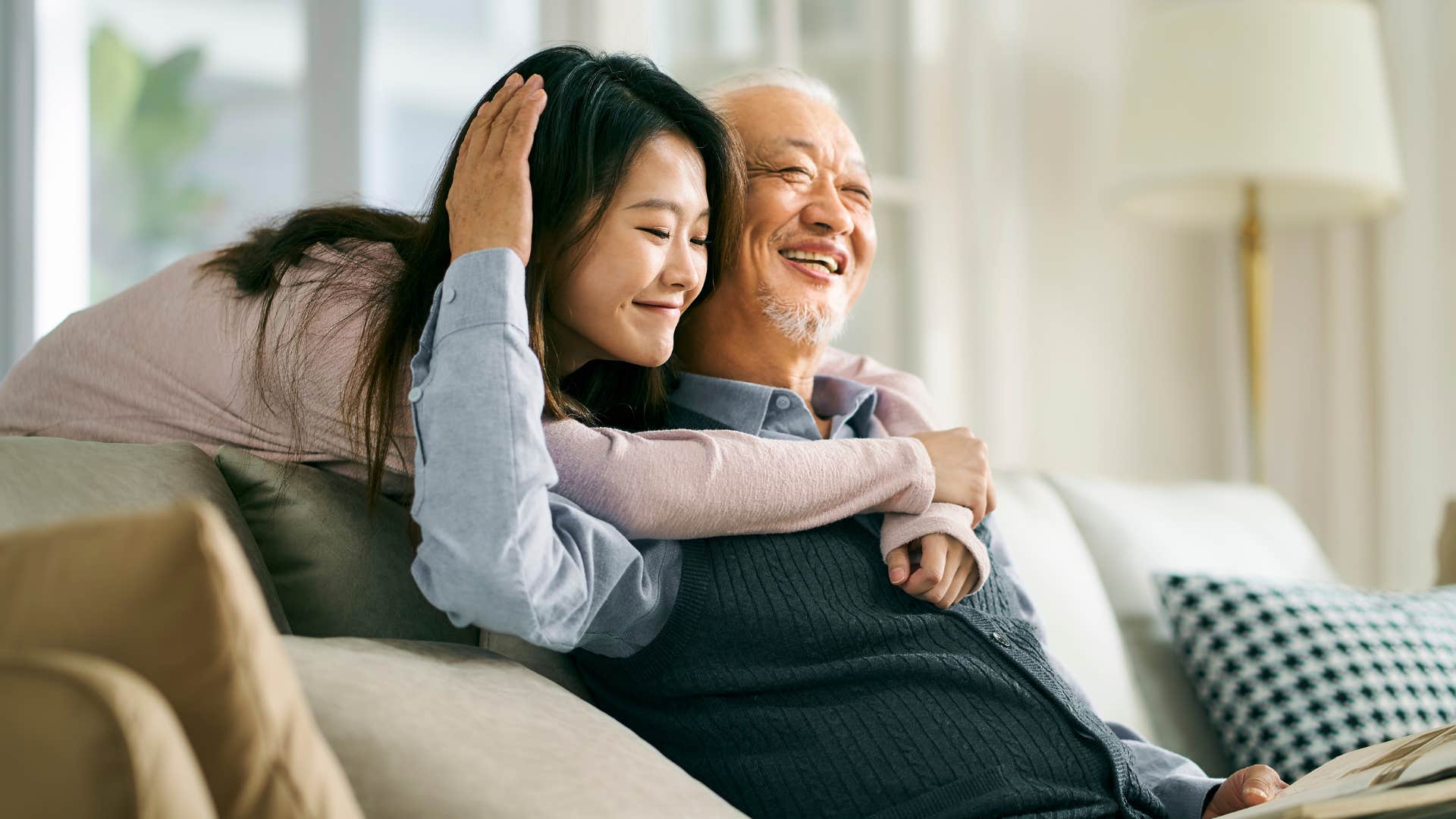 Woman hugging her older dad on the couch.