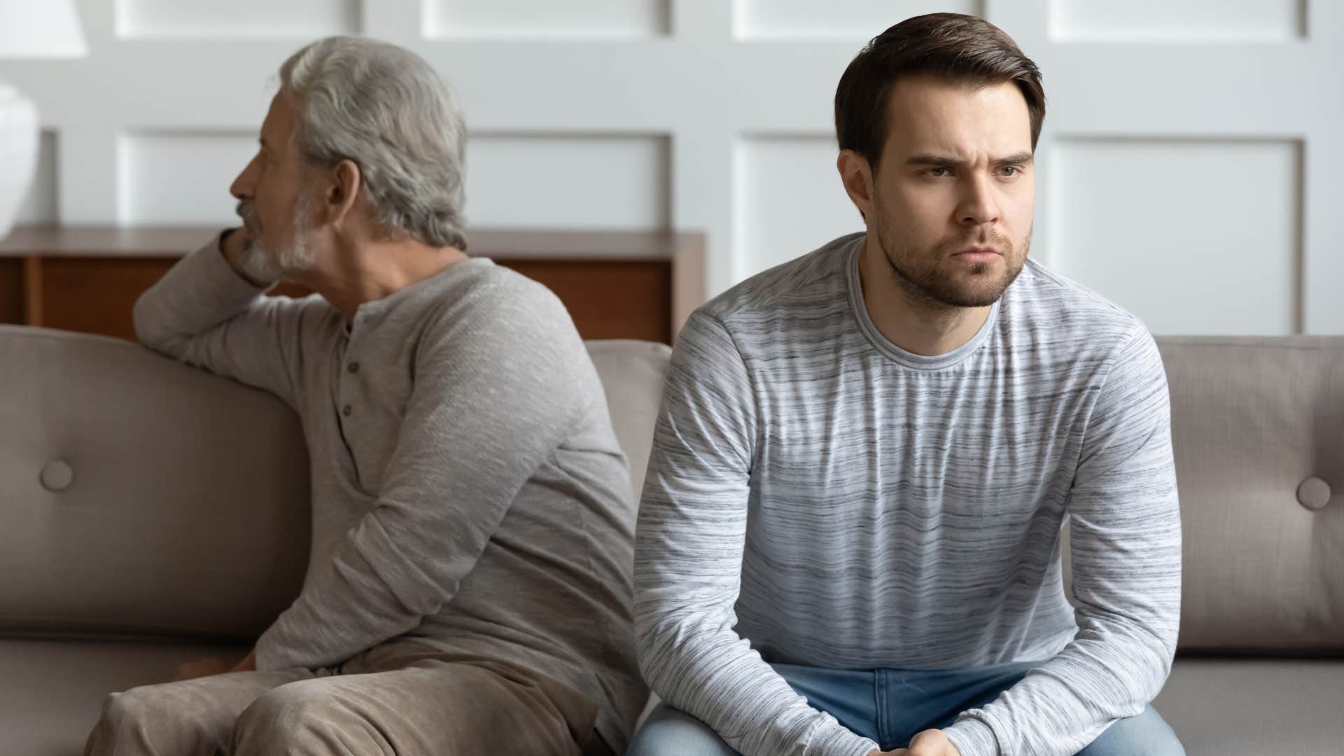 Man looking annoyed sitting next to his dad.