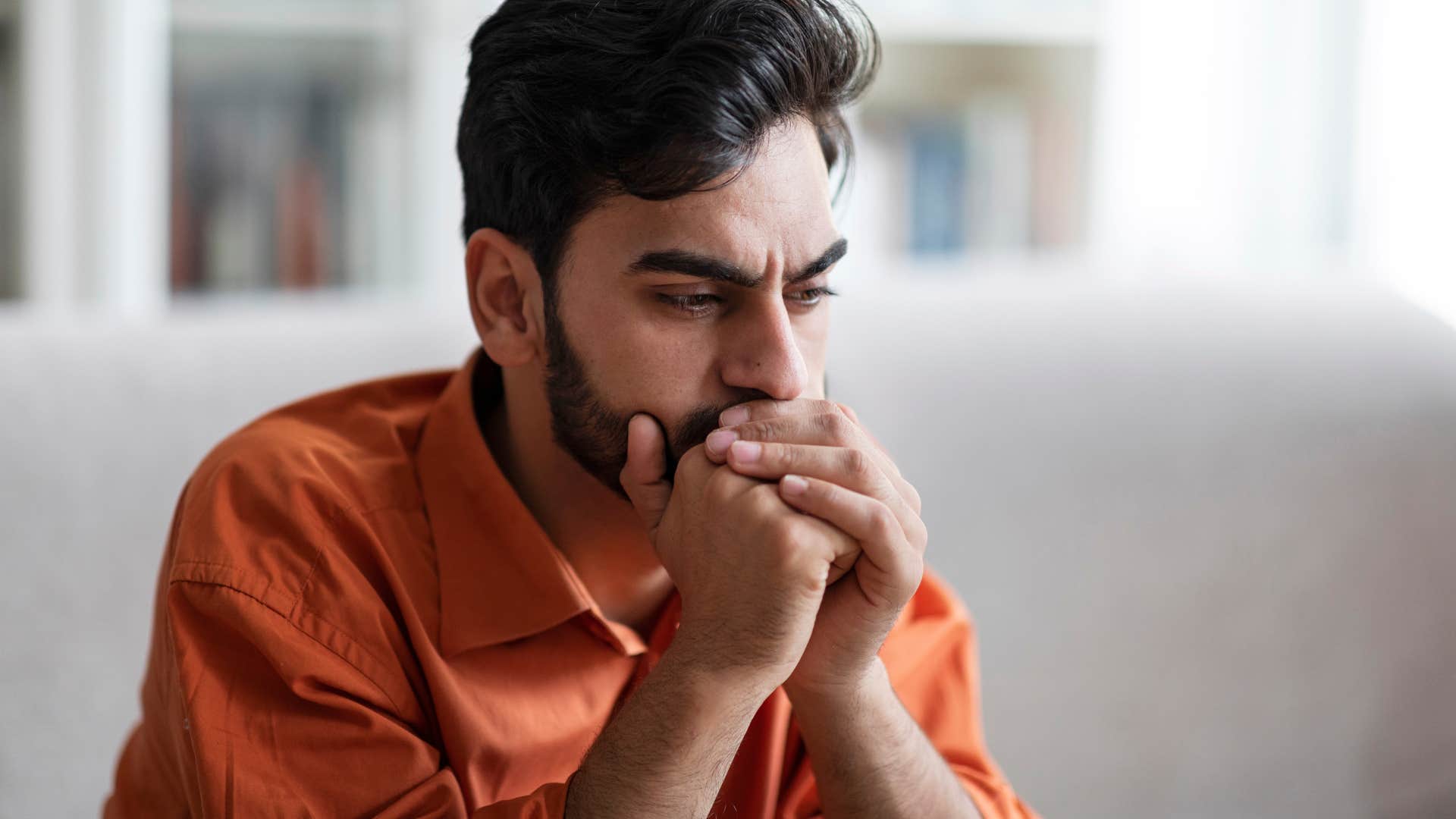 Man looking sad sitting on the couch.