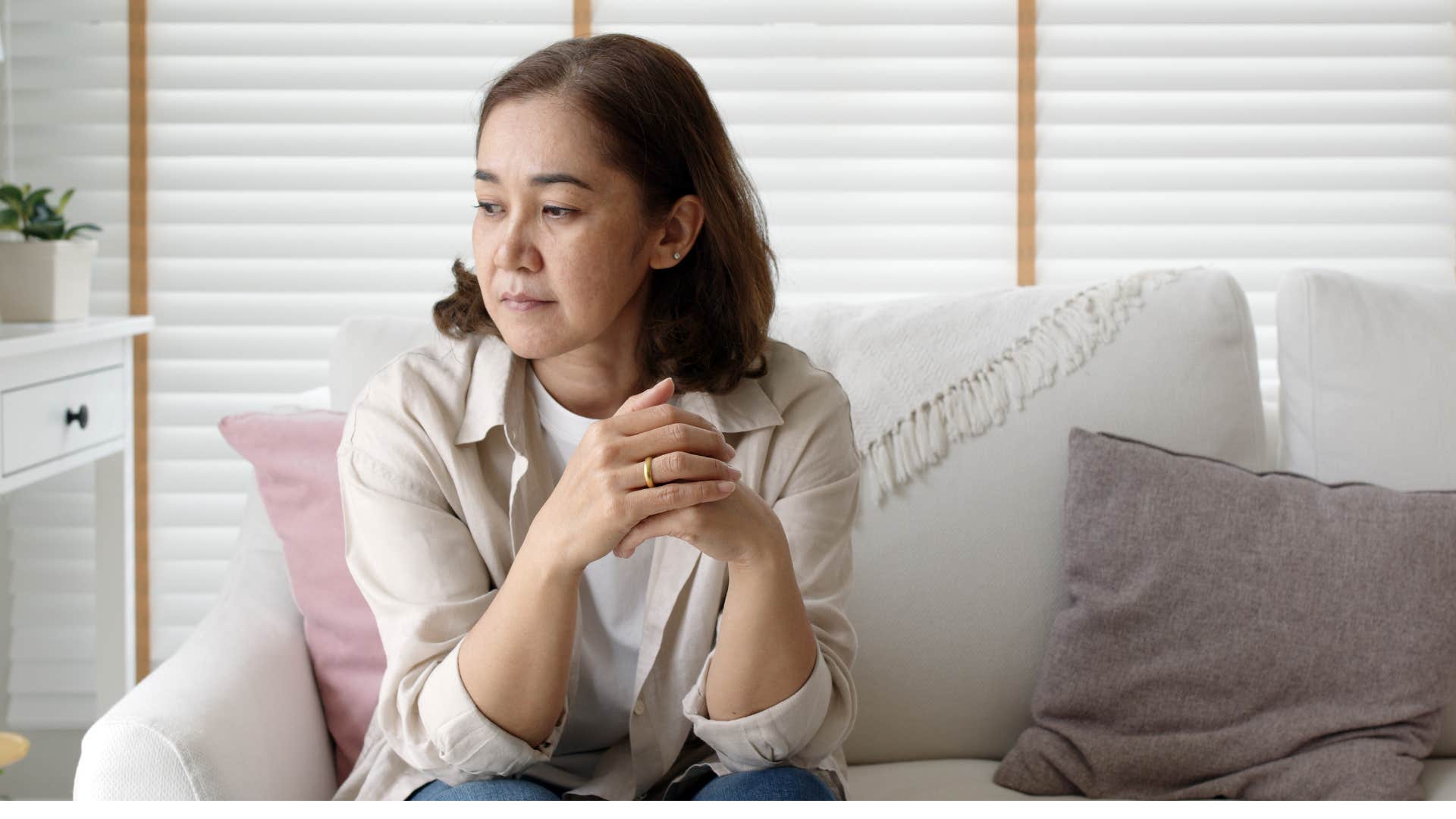 Woman looking annoyed sitting on her couch.