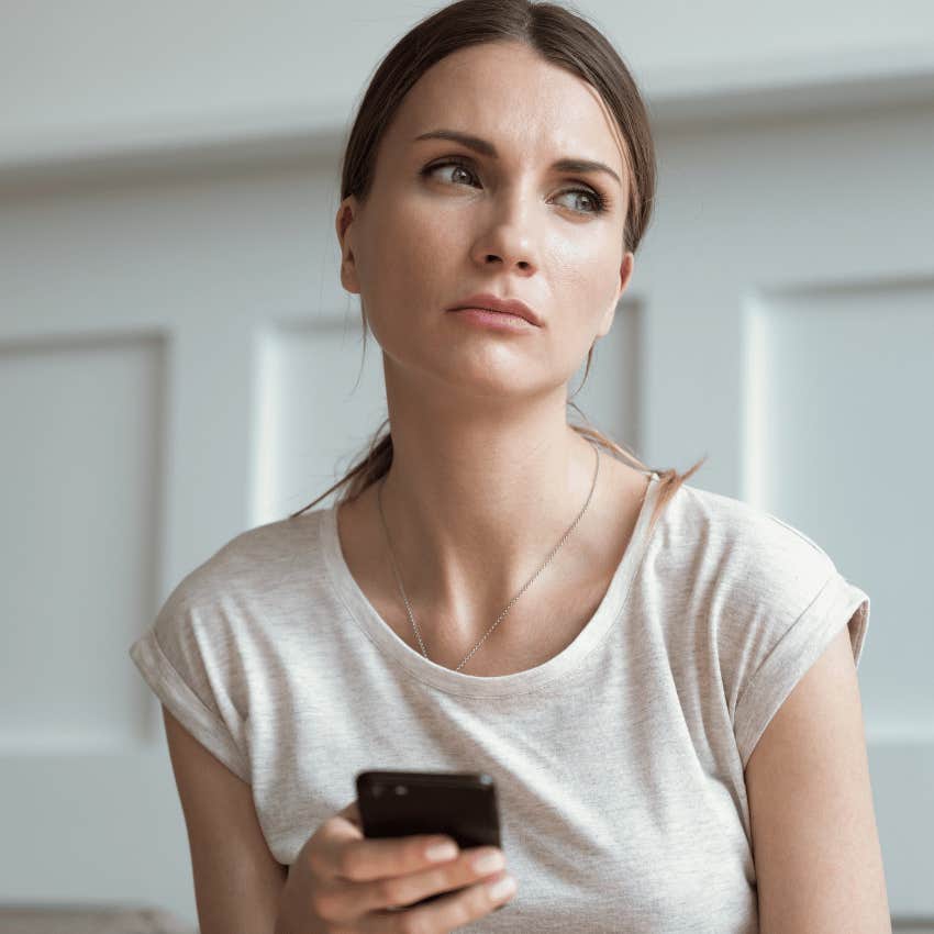 pensive young woman holding her phone