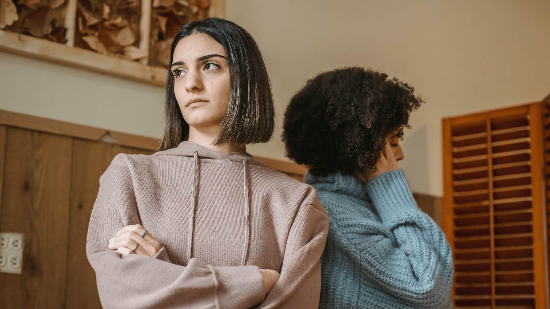 two women with their arms crossed facing away from each other