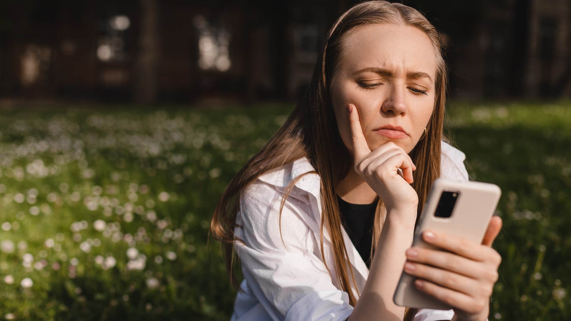 Woman looking annoyed staring at her phone.