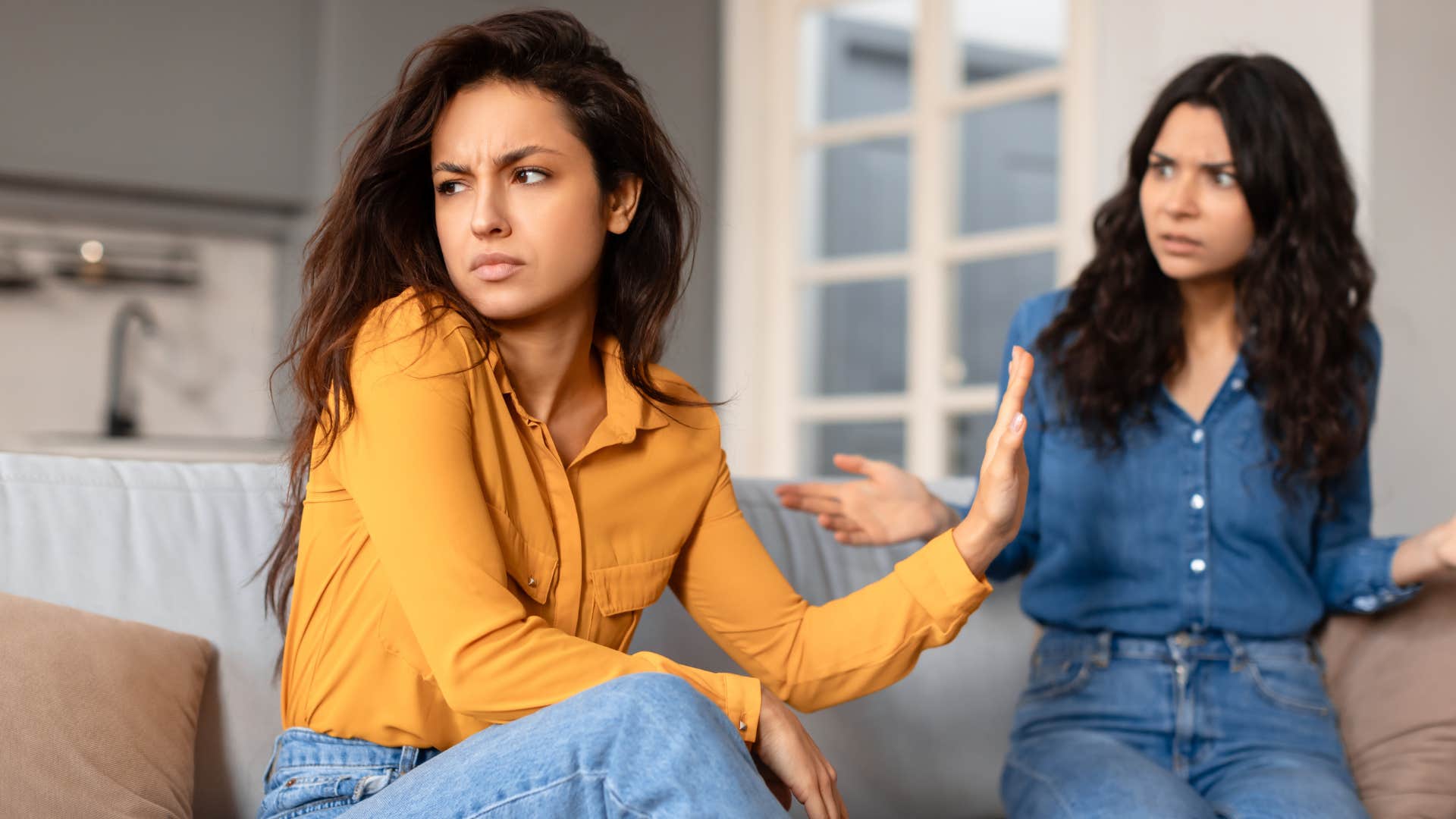 Woman looking annoyed turned away from her friend.