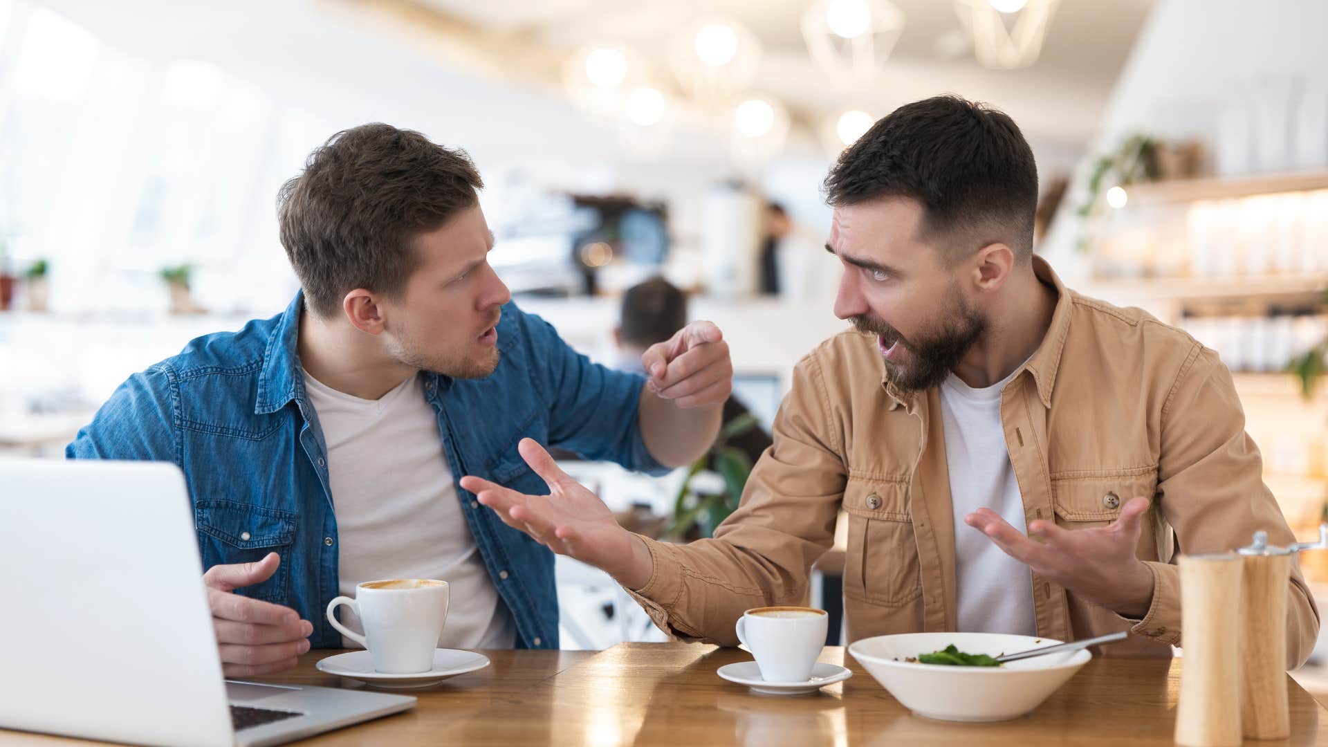 Two men arguing together in a coffee shop.