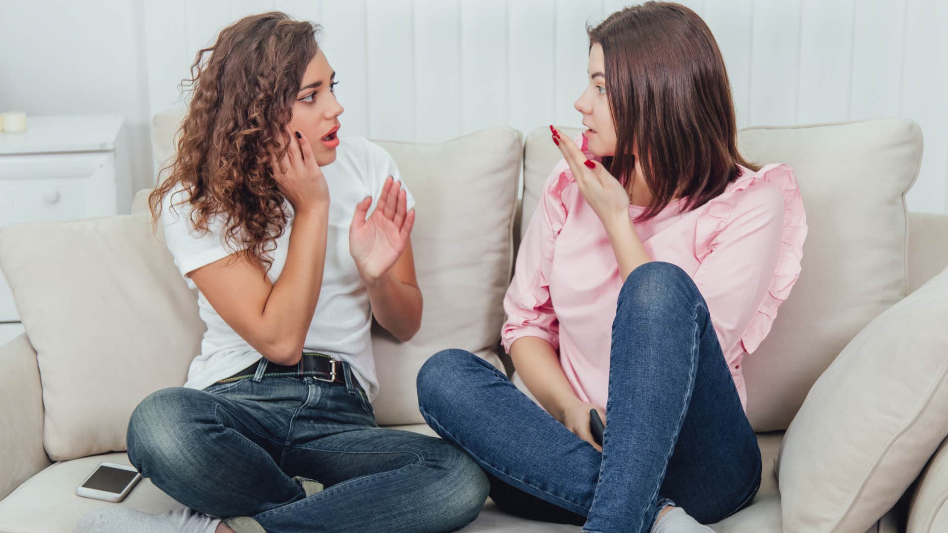 Two friends gossiping on the couch together.