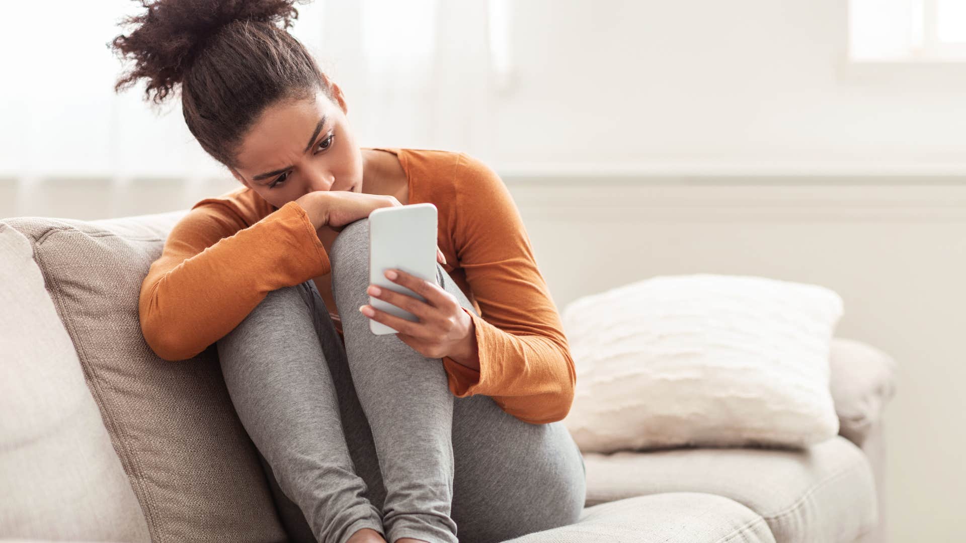 Woman looking sad while staring at her phone. 