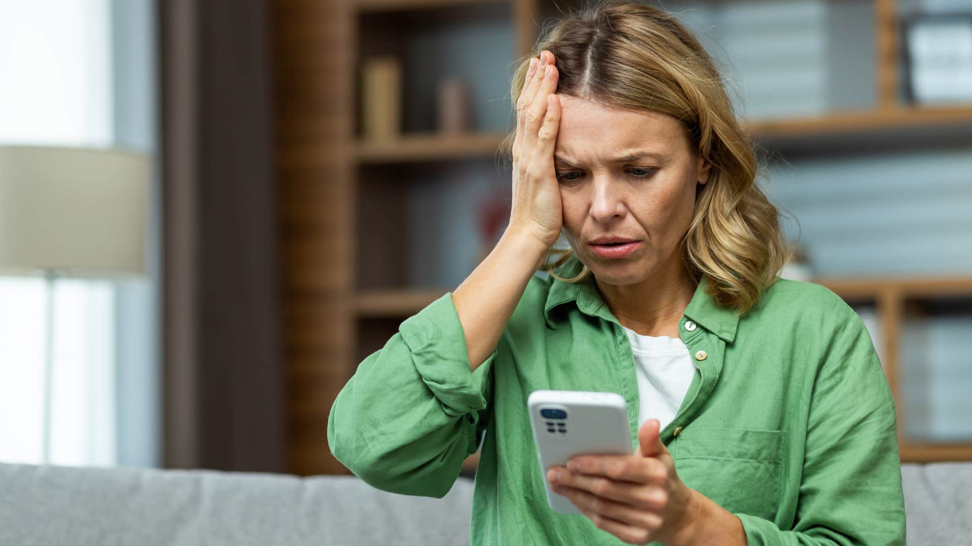 Woman looking stressed staring at her phone.