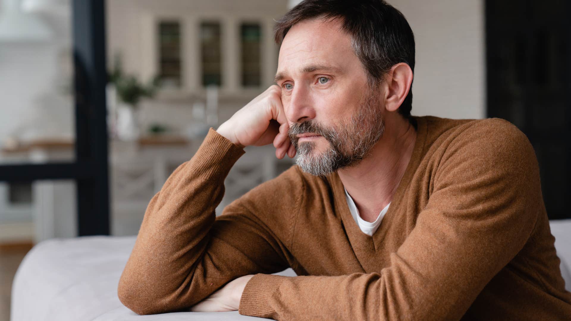 Older man looking stressed staring out the window. 