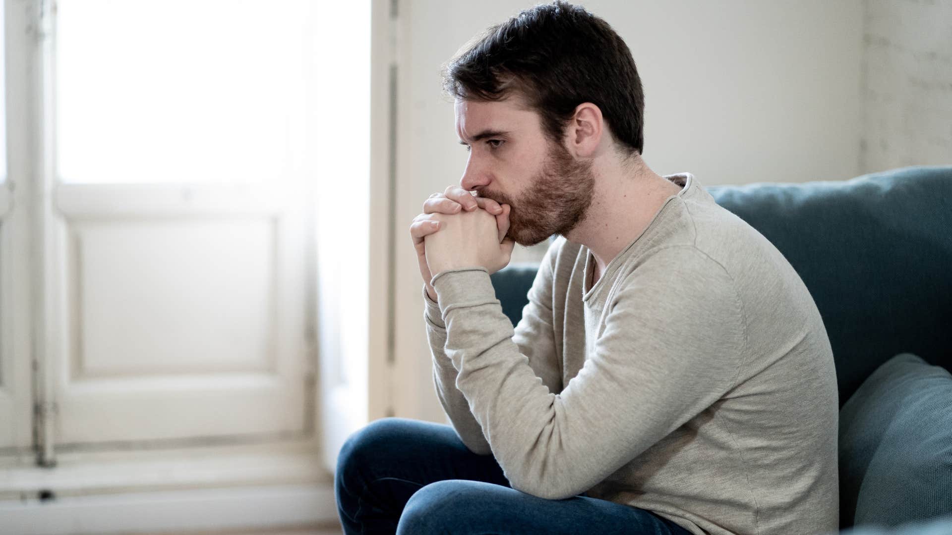 Man looking upset sitting on his couch. 