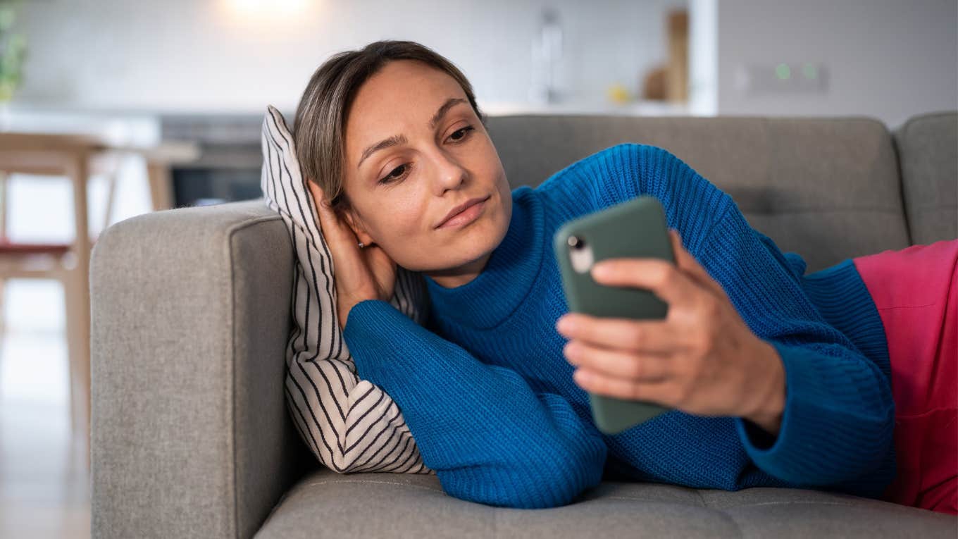 woman on couch watching tv while being on her phone