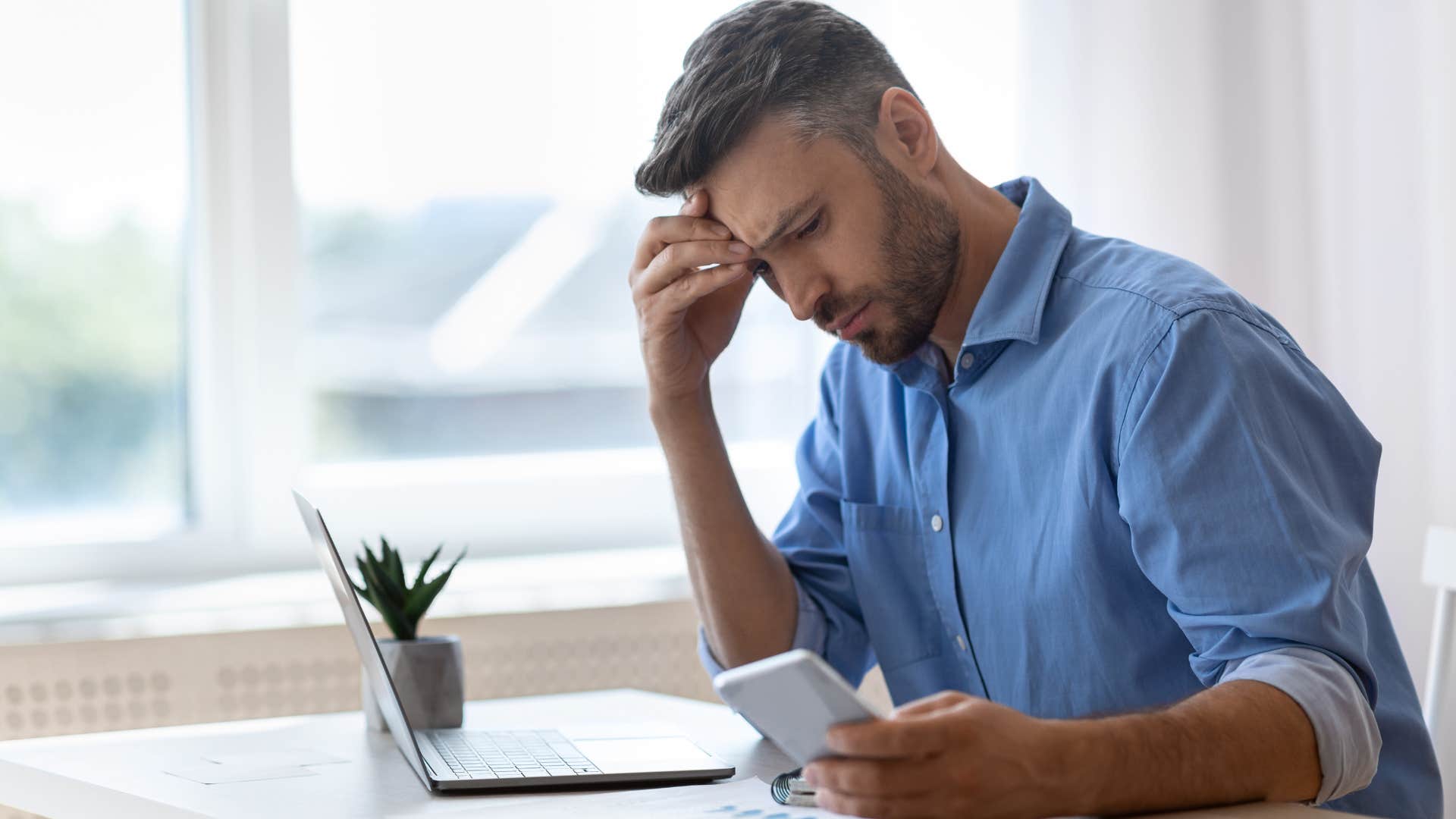 Man looking frustrated while looking on his phone. 