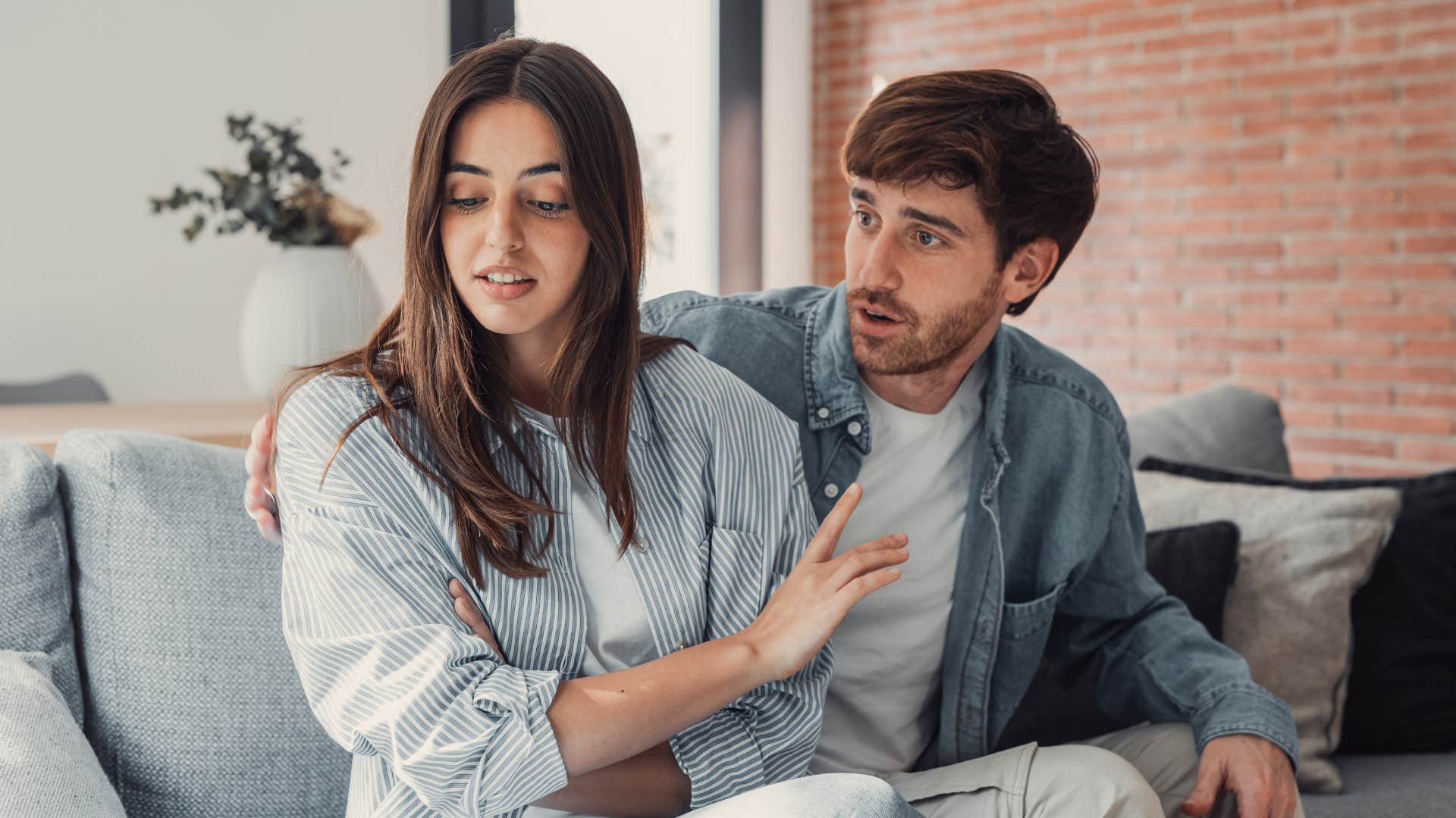 Woman putting her hand up to her boyfriend's face annoyed.