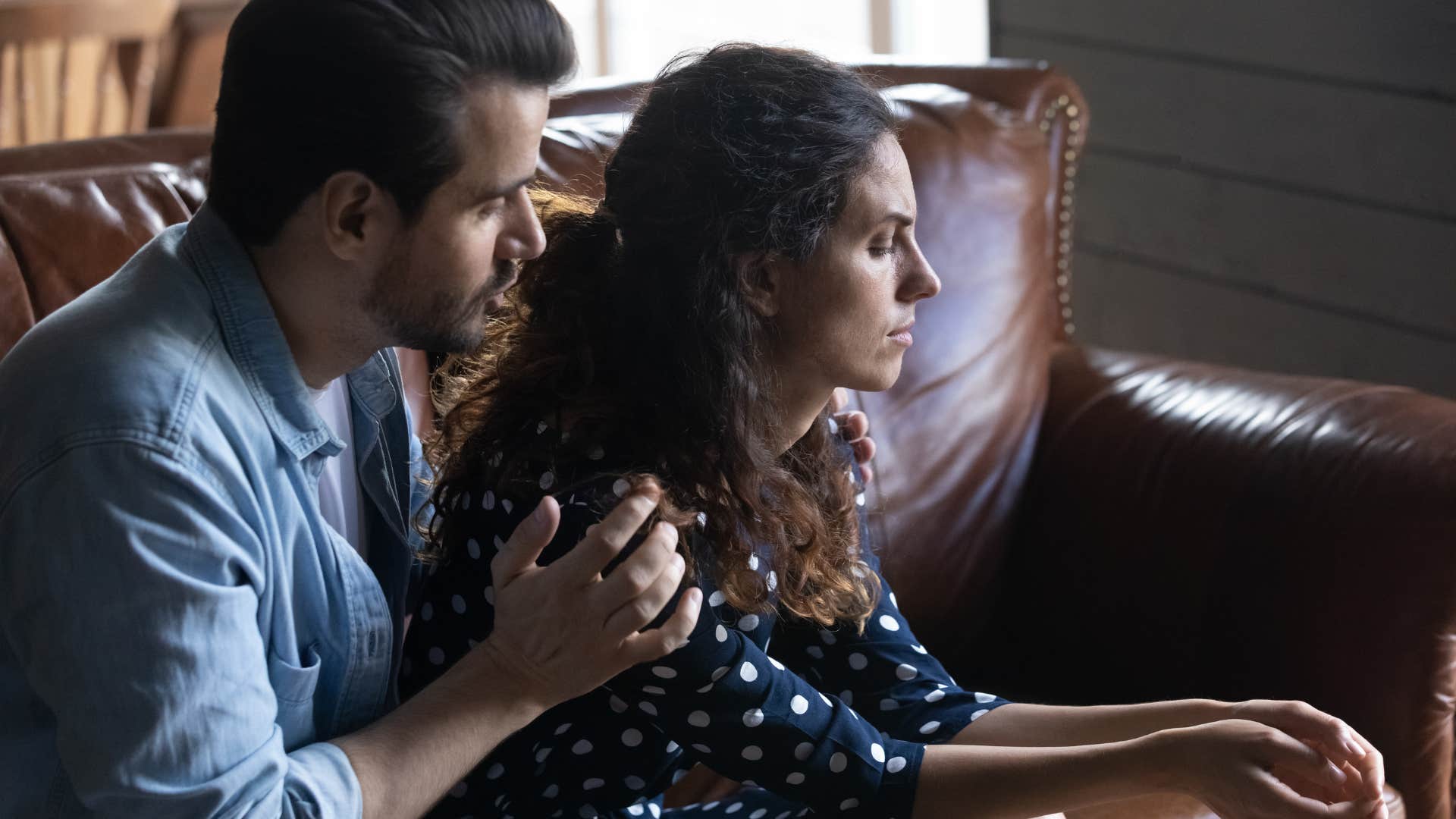 Man comforting his upset wife in their home.