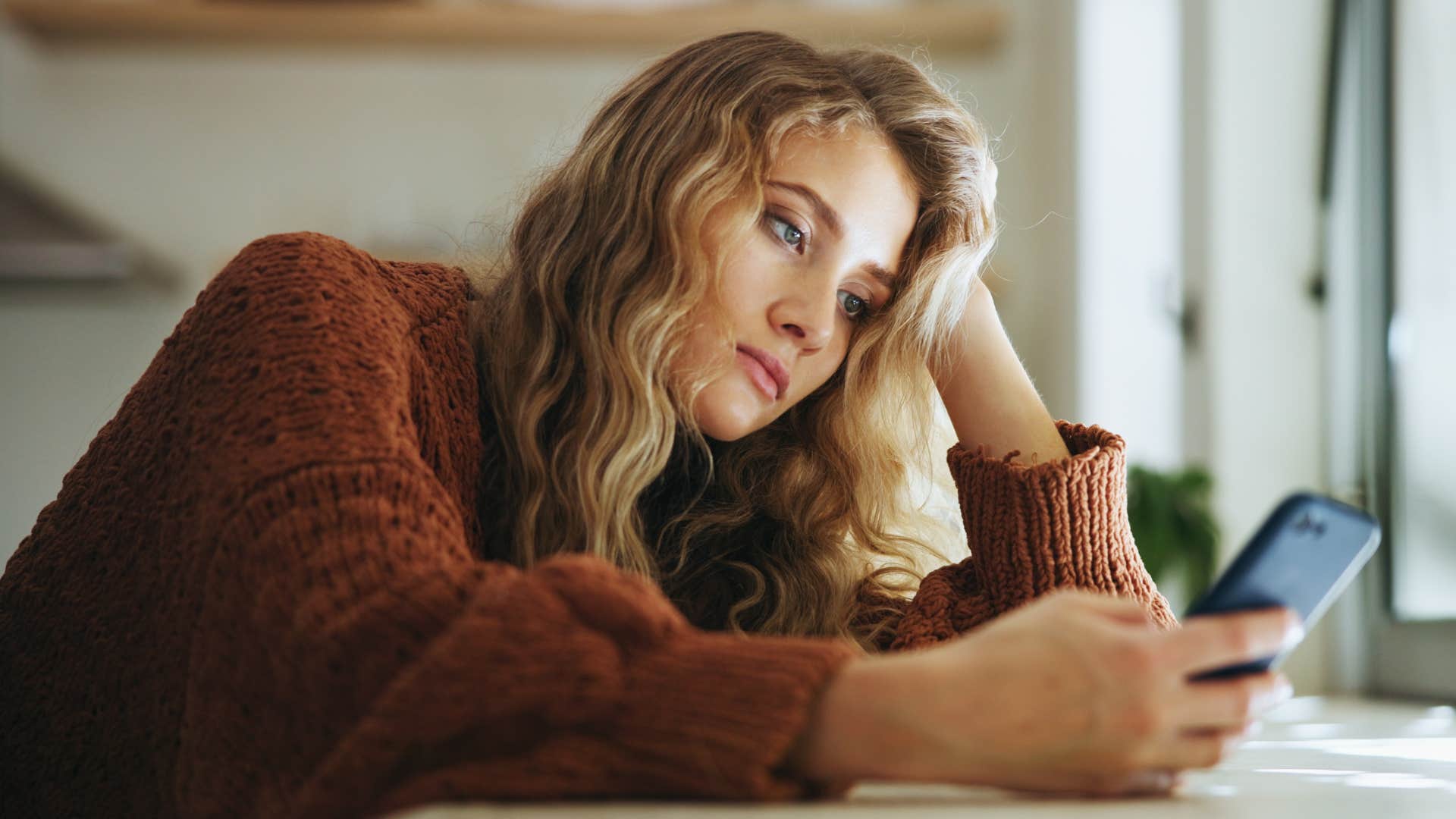 Woman looking annoyed staring at her phone.