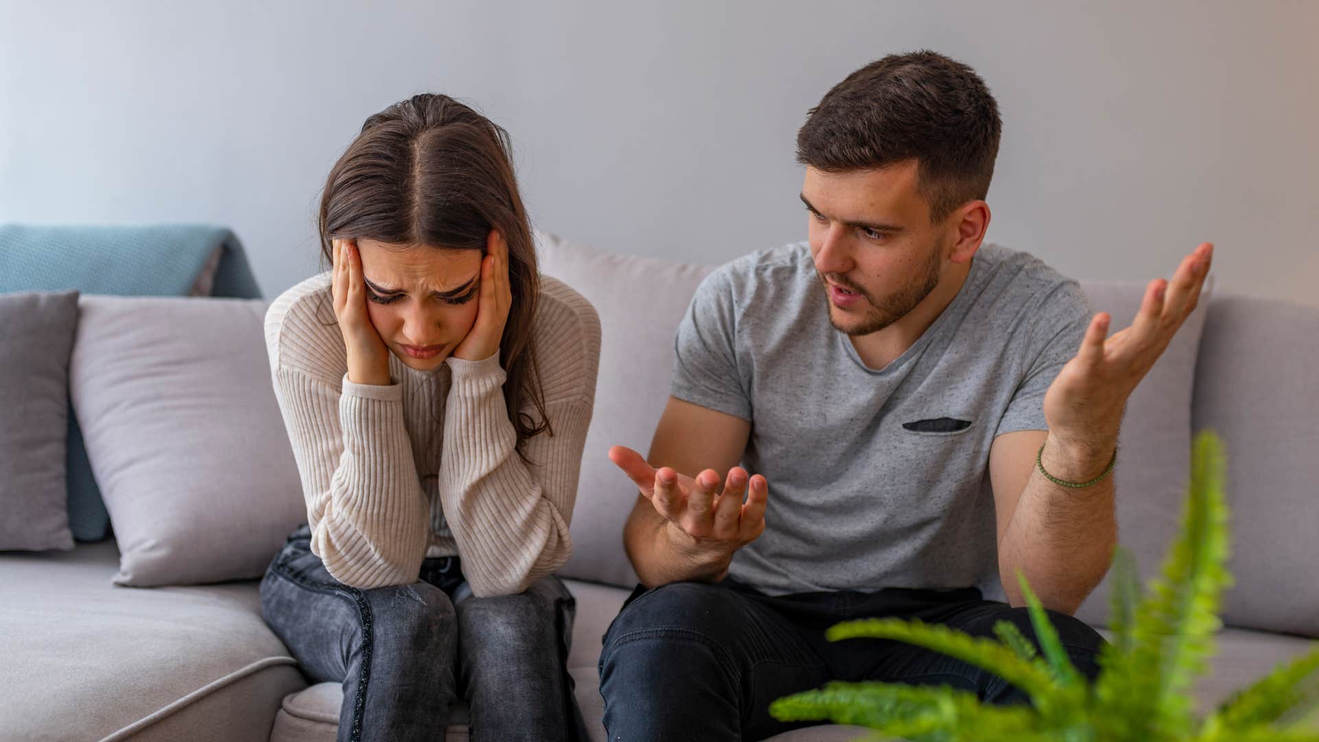 Woman holding her head in her hands with her partner sitting next to her. 