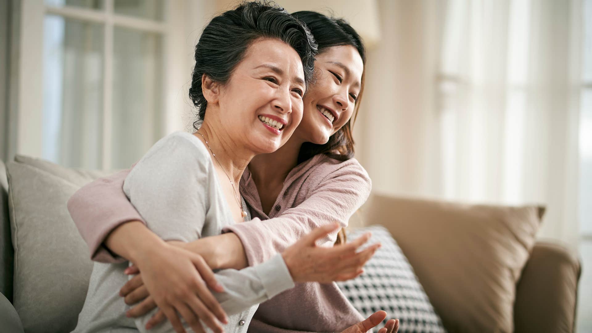 Adult woman smiling while hugging her mom