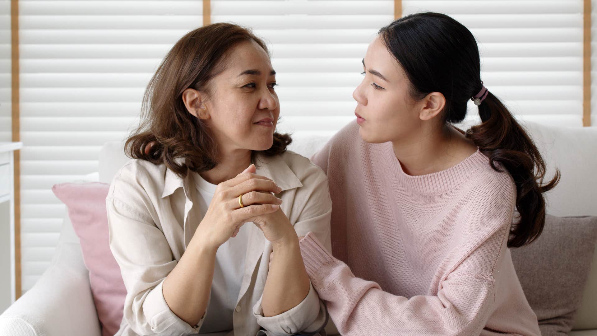 Adult woman comforting her mother on the couch