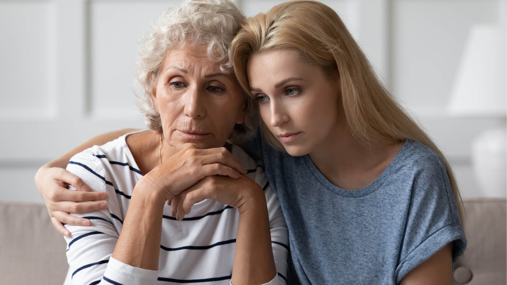 Adult daughter hugging her mom looking upset